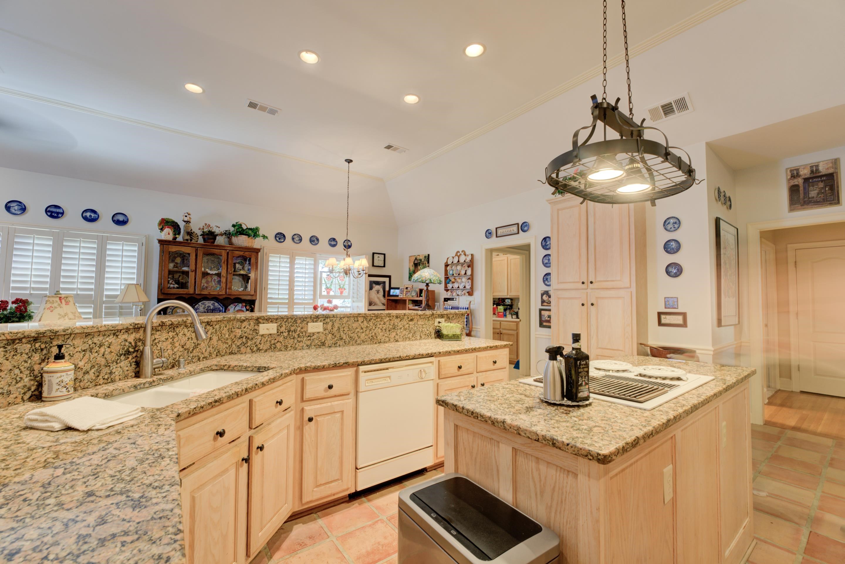 Kitchen with light tile flooring, pendant lighting, light stone counters, white dishwasher, and sink