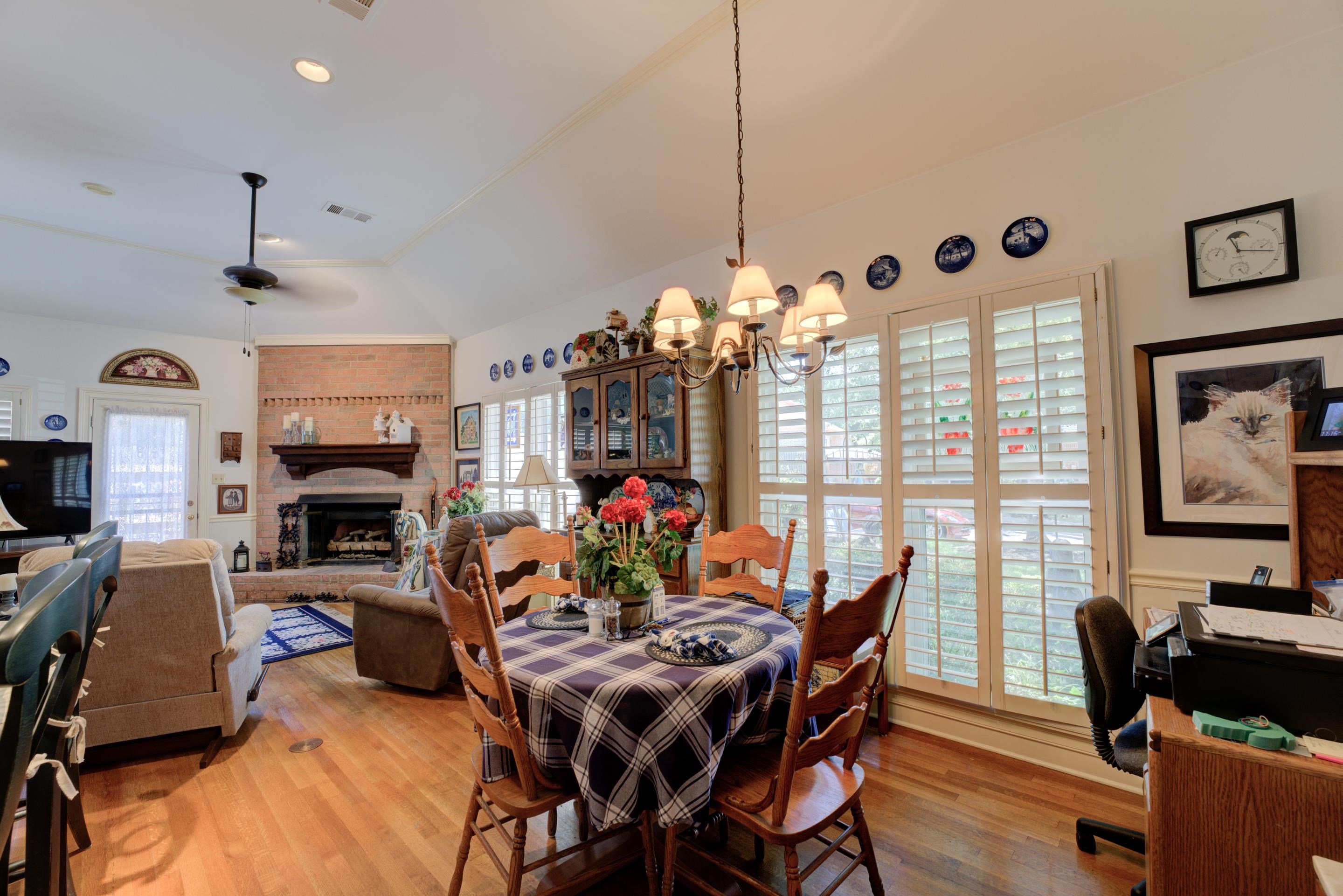 Keeping area with ceiling fan with notable chandelier, hardwood / wood-style flooring, a fireplace, and lofted ceiling