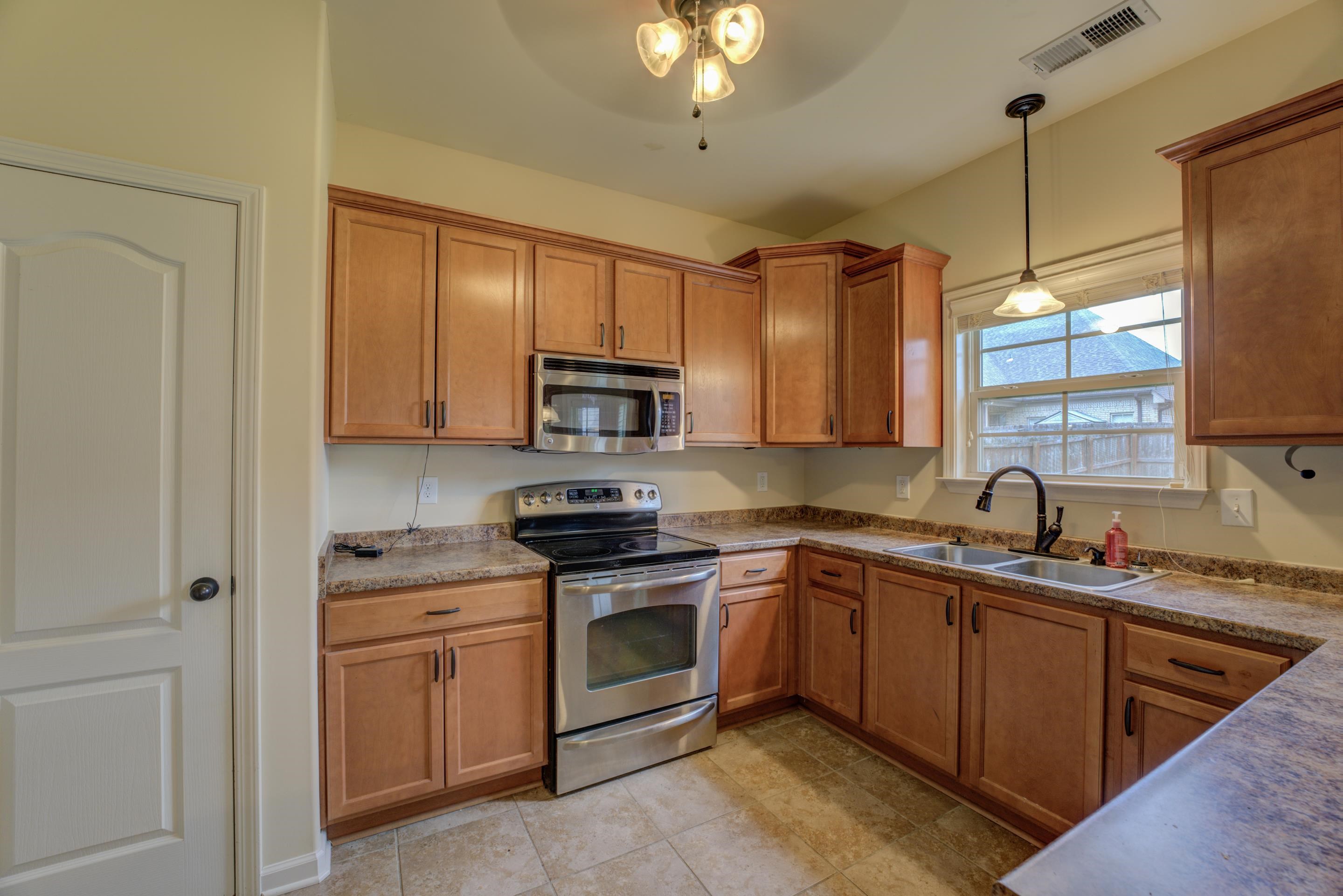 Kitchen with sink, tile floors, pendant lighting, ceiling fan, and appliances with stainless steel finishes.