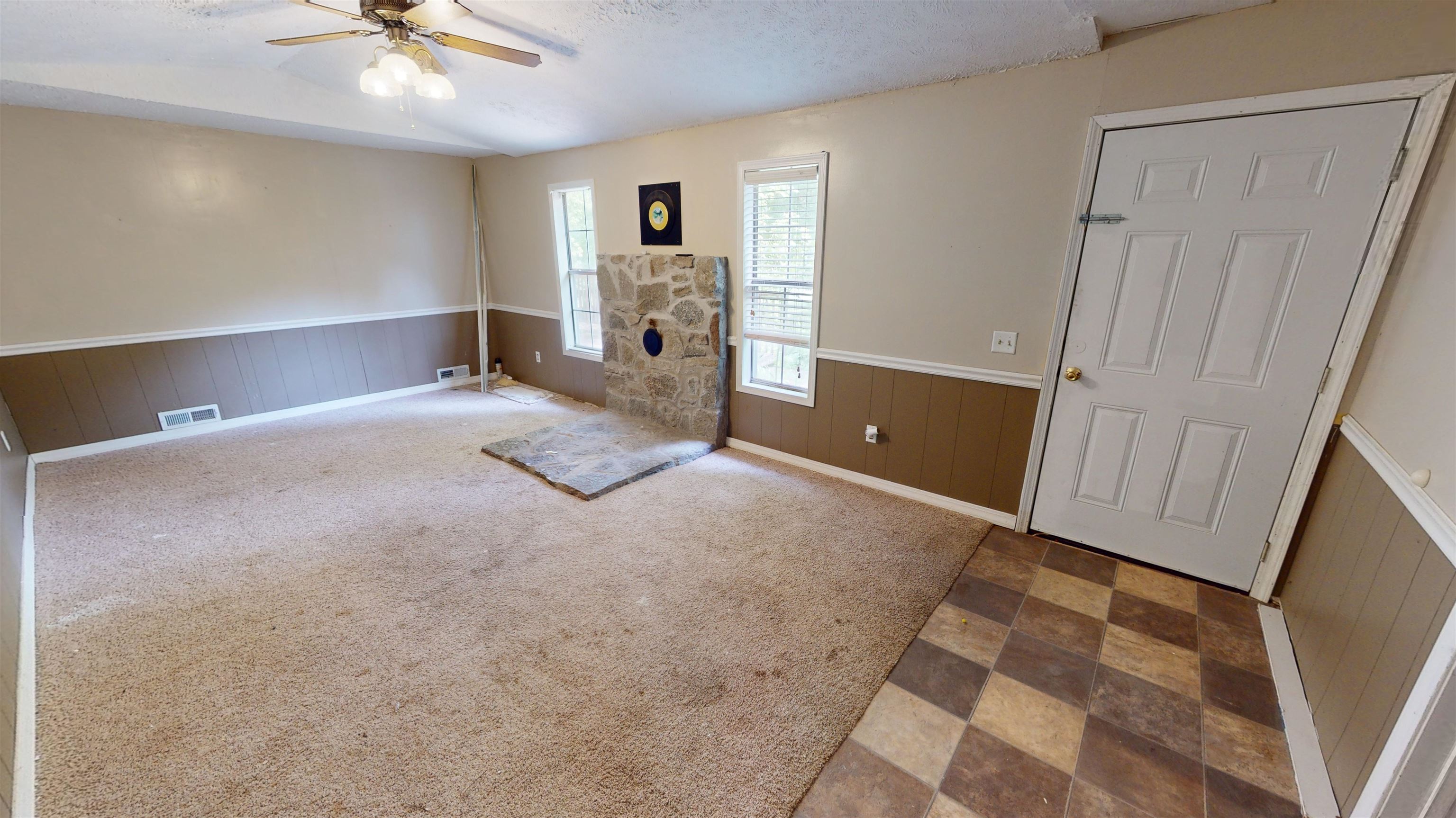 Interior space with light colored carpet, ceiling fan, a textured ceiling, and lofted ceiling