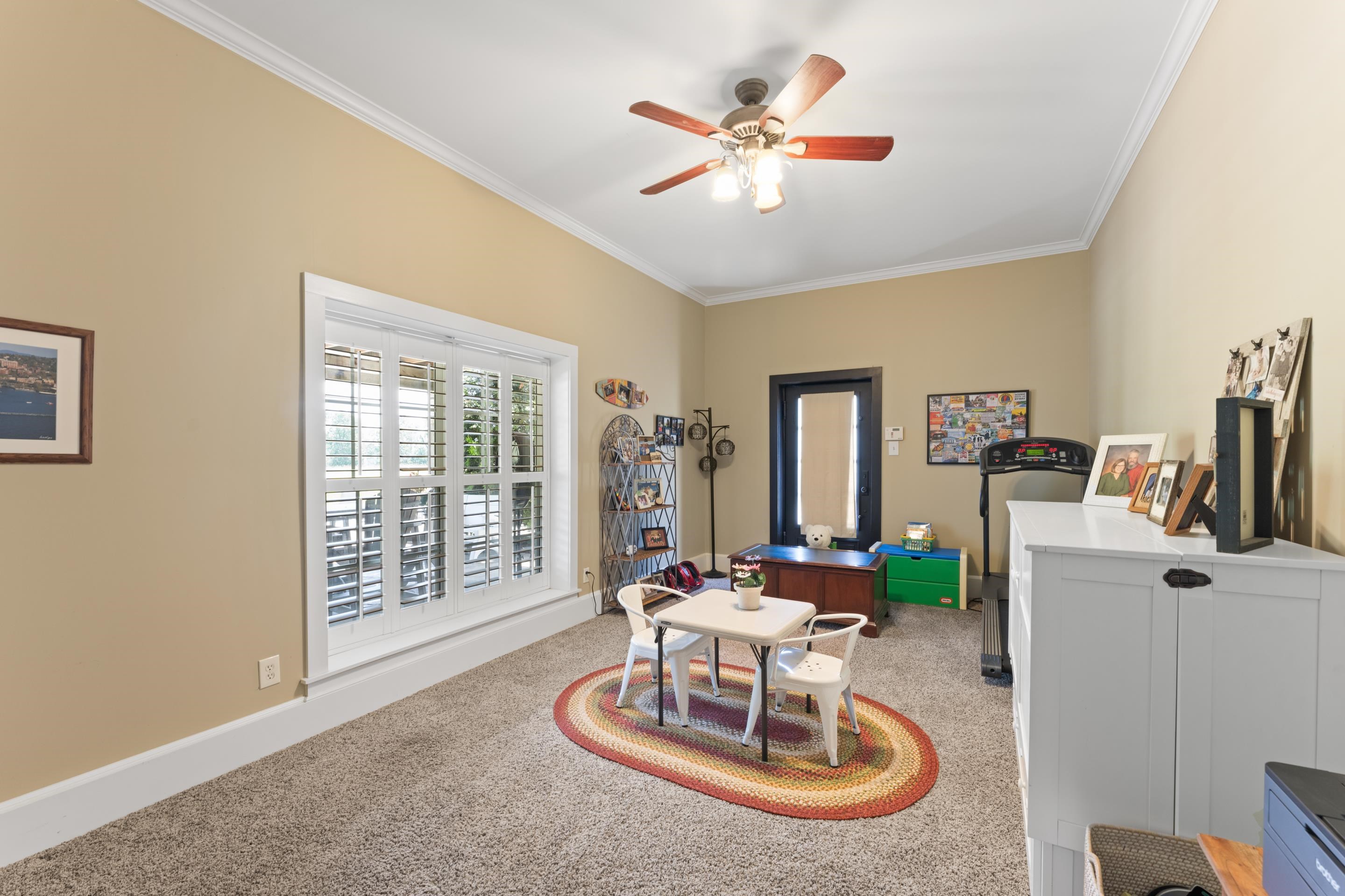 Rec room featuring carpet, ceiling fan, and crown molding