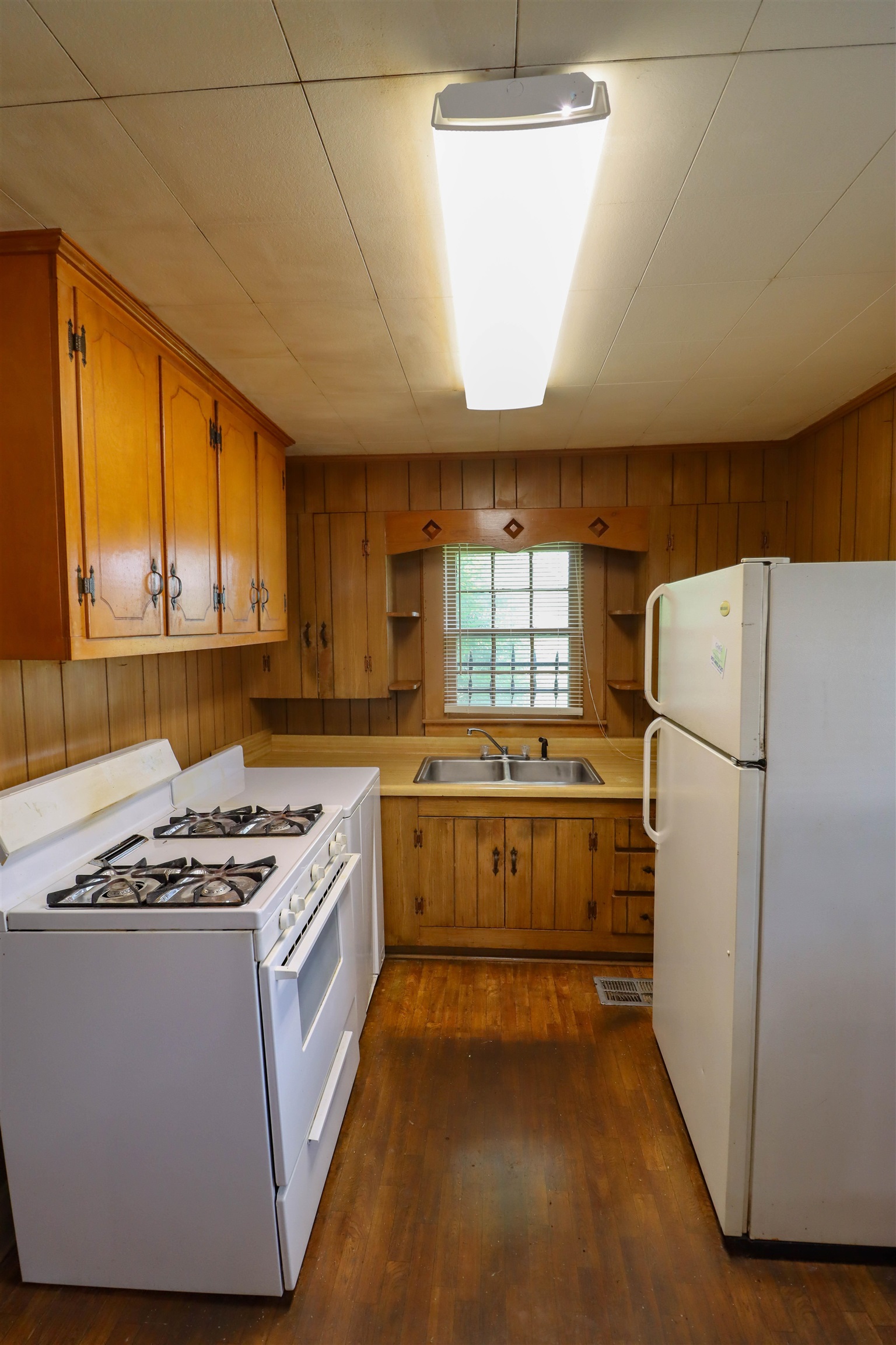 Kitchen with dark wood-type flooring, sink, and white appliances