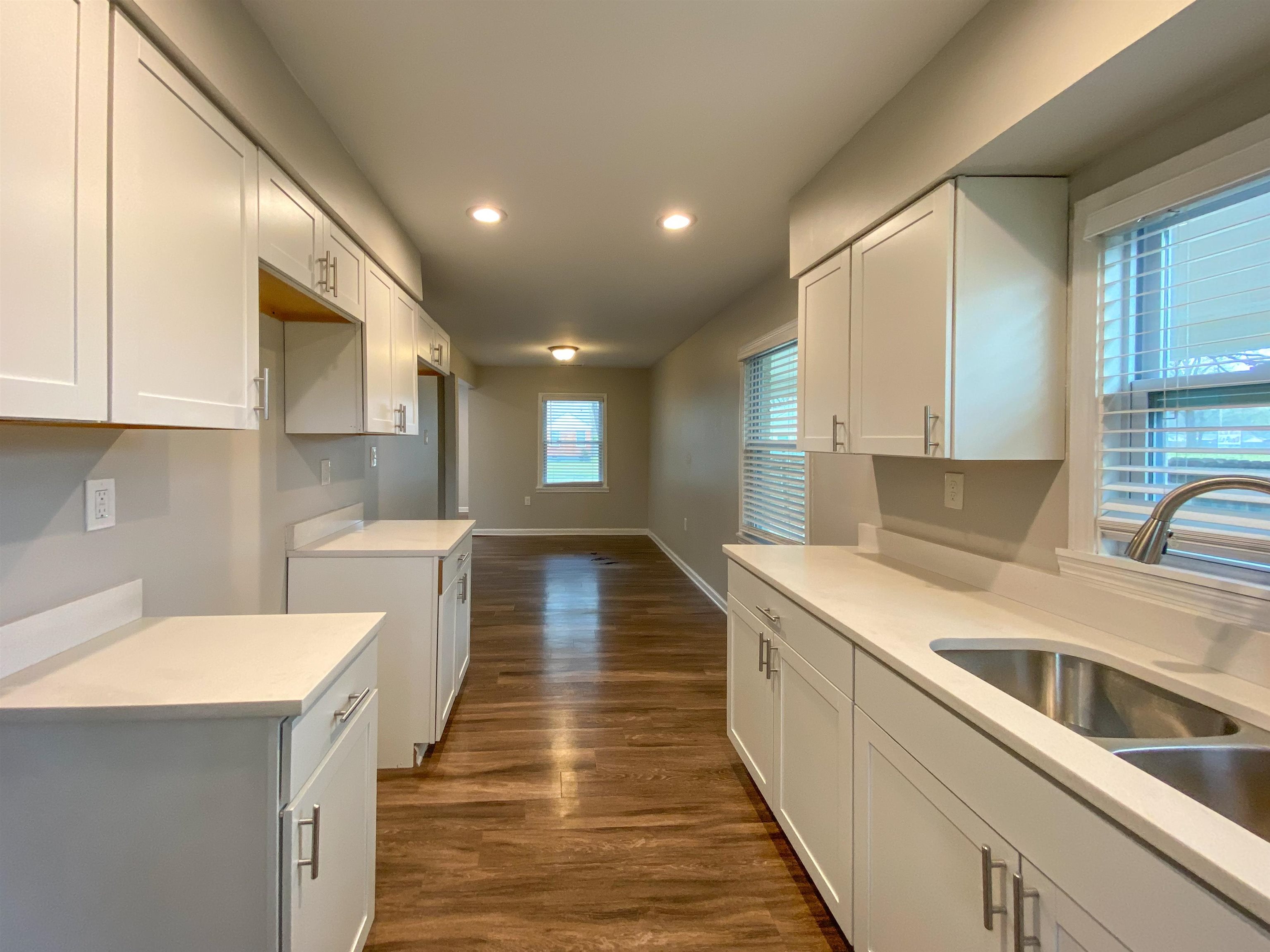 Kitchen featuring dark wood-type flooring, white cabinets, and sink