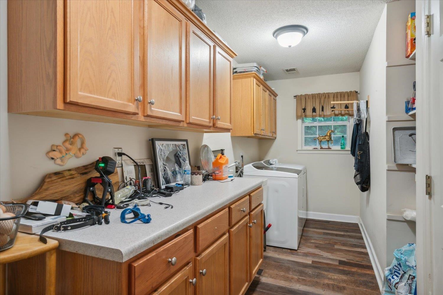 Washroom featuring independent washer and dryer, a textured ceiling, cabinets, and dark wood-type flooring