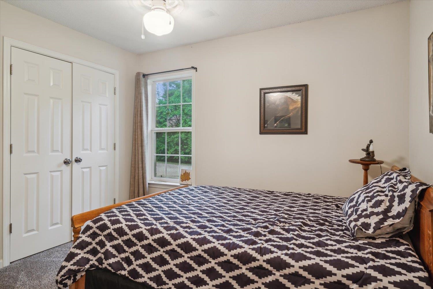 Carpeted bedroom featuring a closet and ceiling fan
