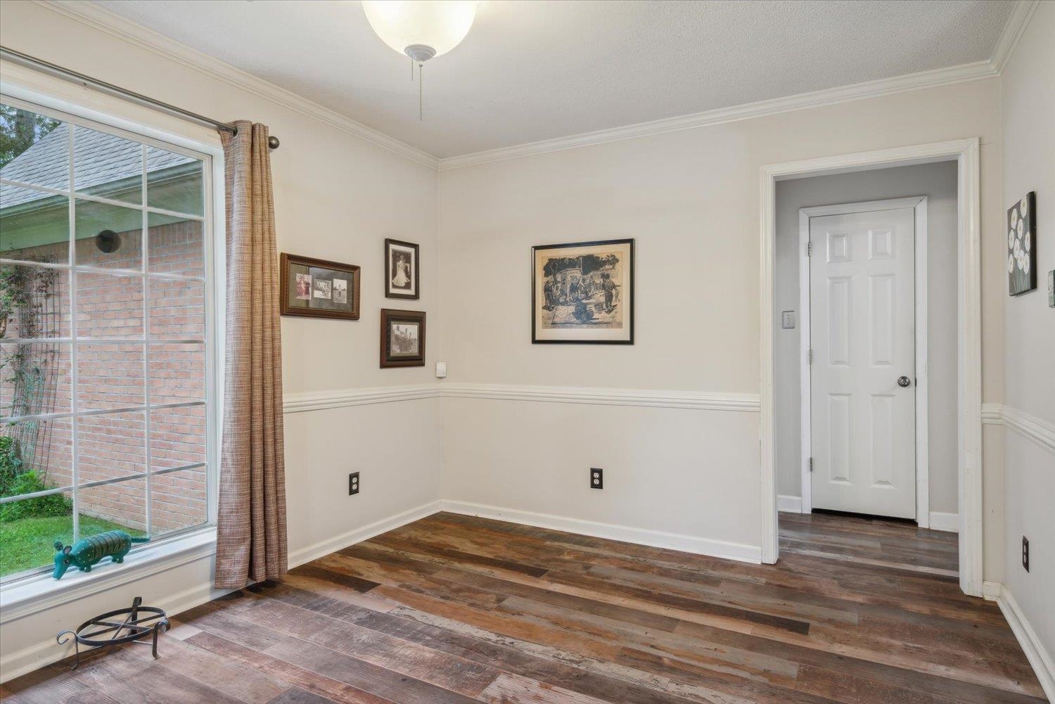 Unfurnished room with a wealth of natural light, dark wood-type flooring, and ornamental molding