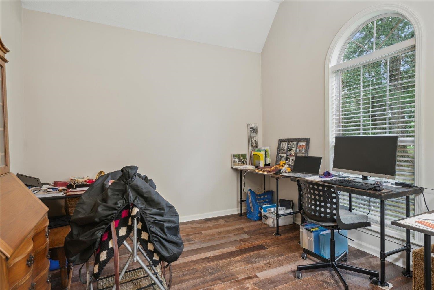 Home office with dark hardwood / wood-style flooring and lofted ceiling