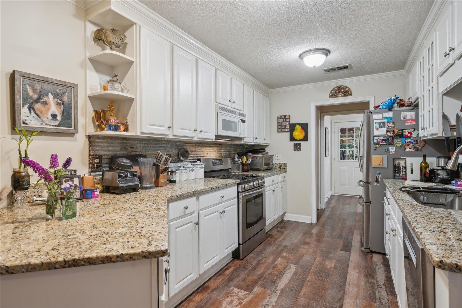 Kitchen with stainless steel range, white cabinets, and dark hardwood / wood-style flooring
