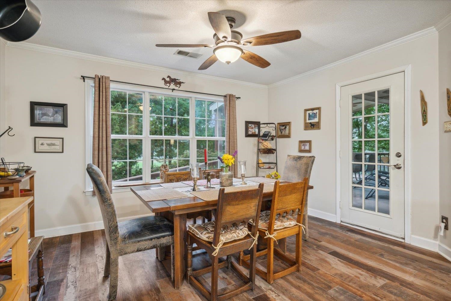 Dining area with ceiling fan, ornamental molding, and dark wood-type flooring