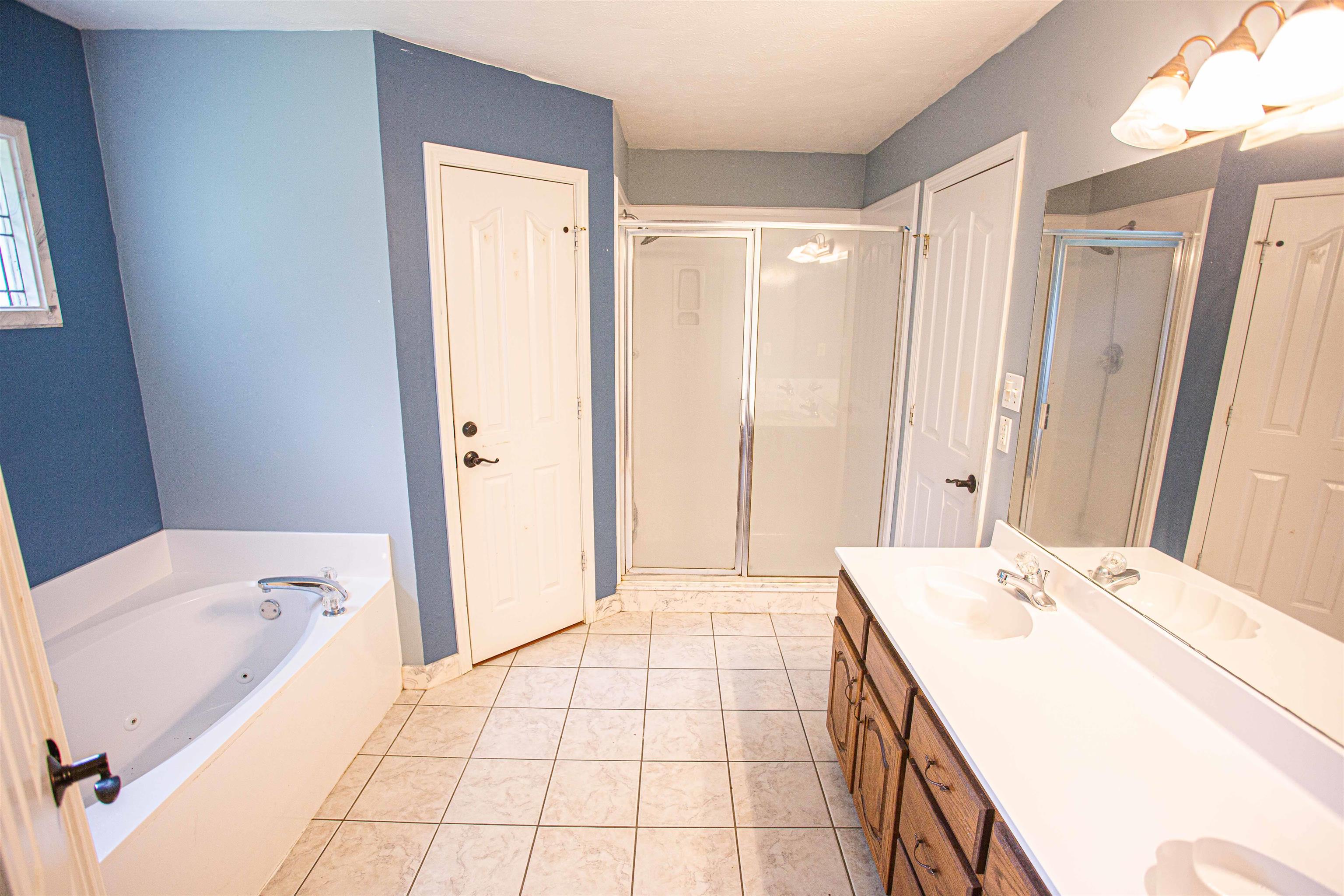 Bathroom featuring tile floors, separate shower and tub, and double sink vanity