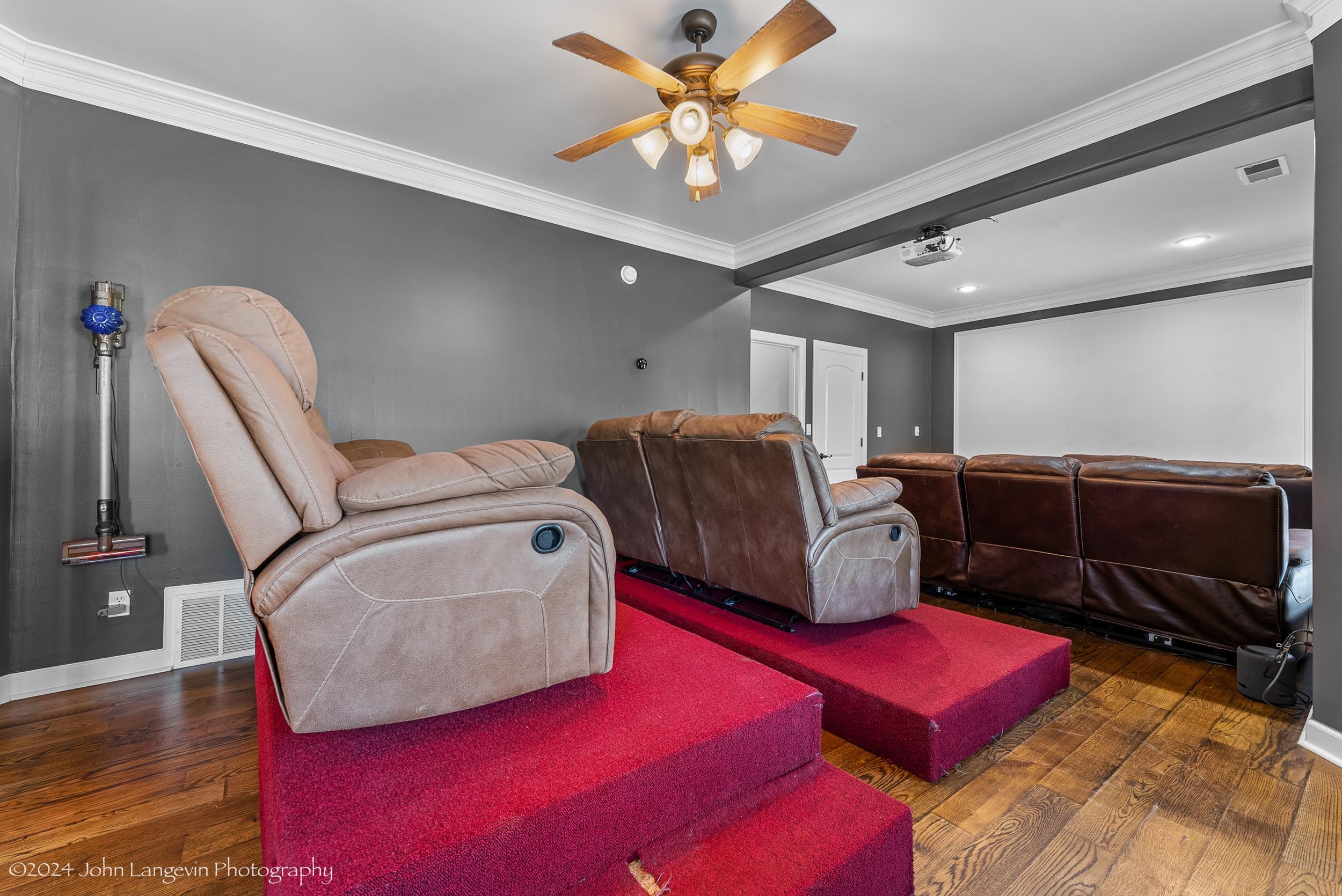 Home theater featuring crown molding, dark hardwood / wood-style floors, and ceiling fan