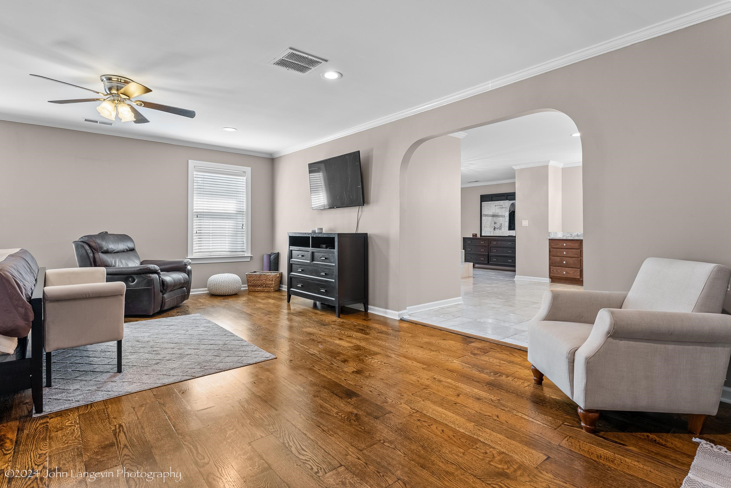 Living room featuring wood-type flooring, ornamental molding, and ceiling fan