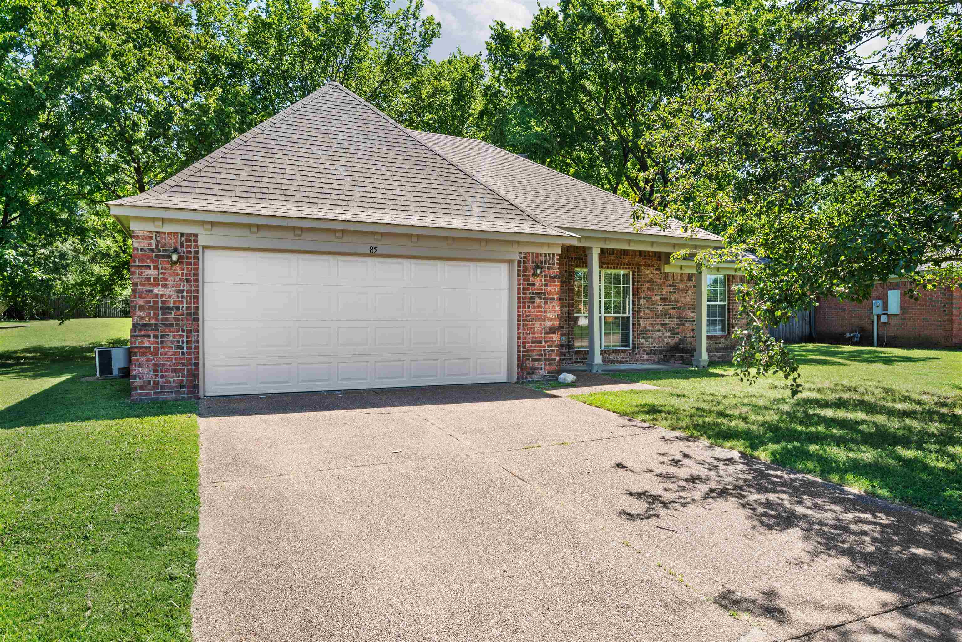 View of front of property with a 2-car garage, a large front lawn, and a covered front porch area.