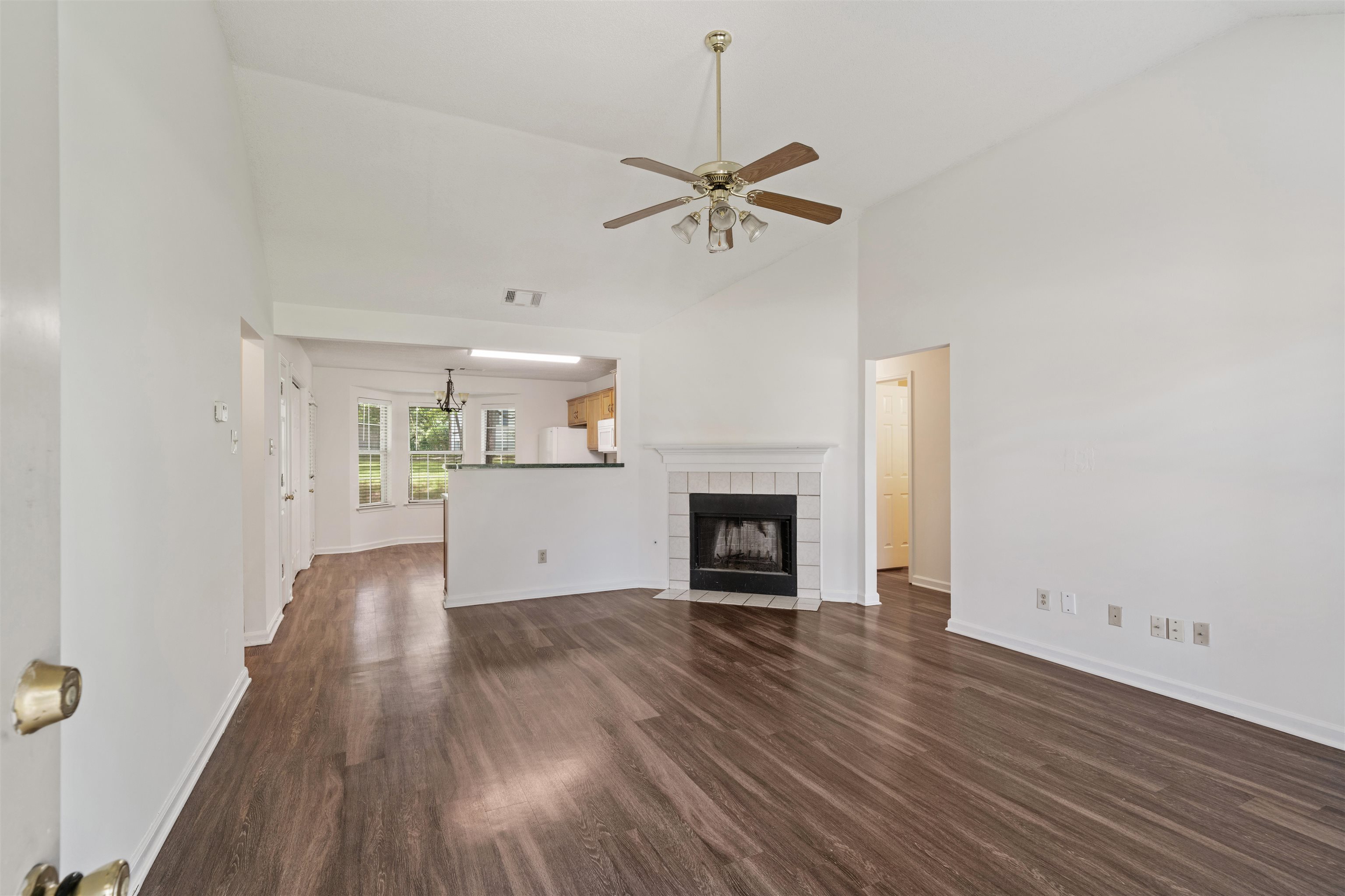 Living room featuring a tile fireplace, high vaulted ceiling, dark hardwood / wood-style floors, and ceiling fan.