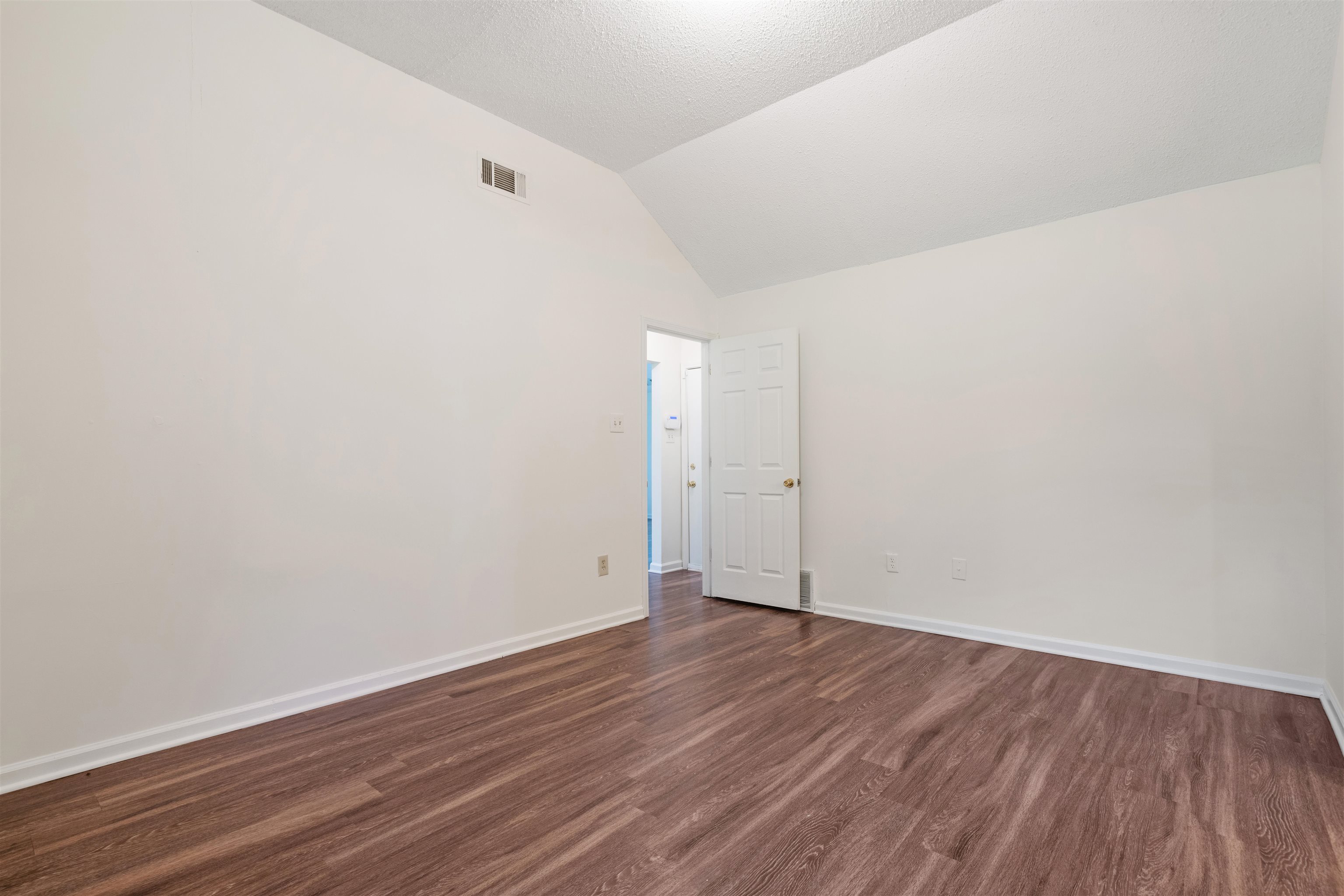 Primary Bedroom with dark wood-type flooring and vaulted ceiling