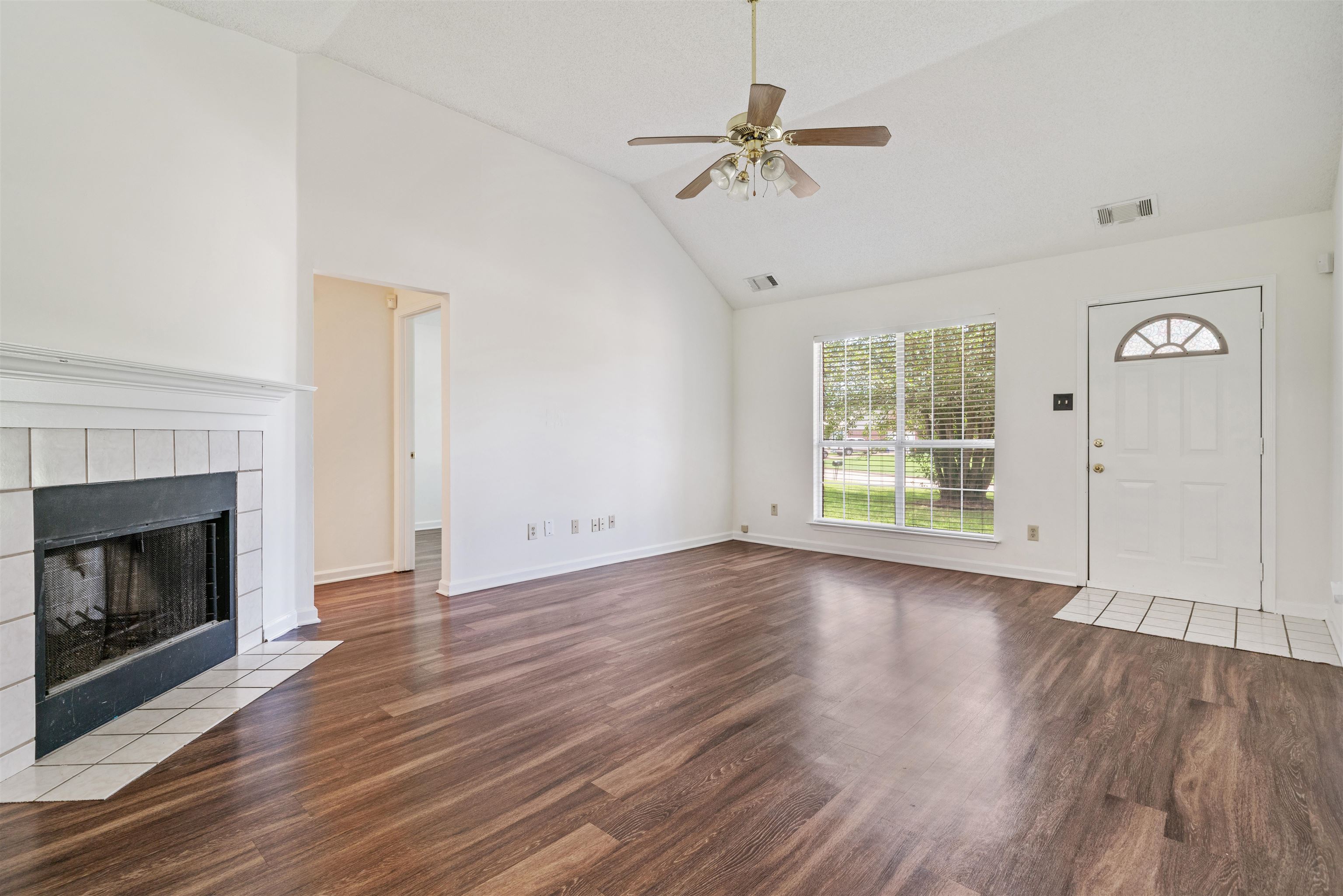 Living Room featuring a tile fireplace, ceiling fan, hardwood / wood-style flooring, and high vaulted ceiling