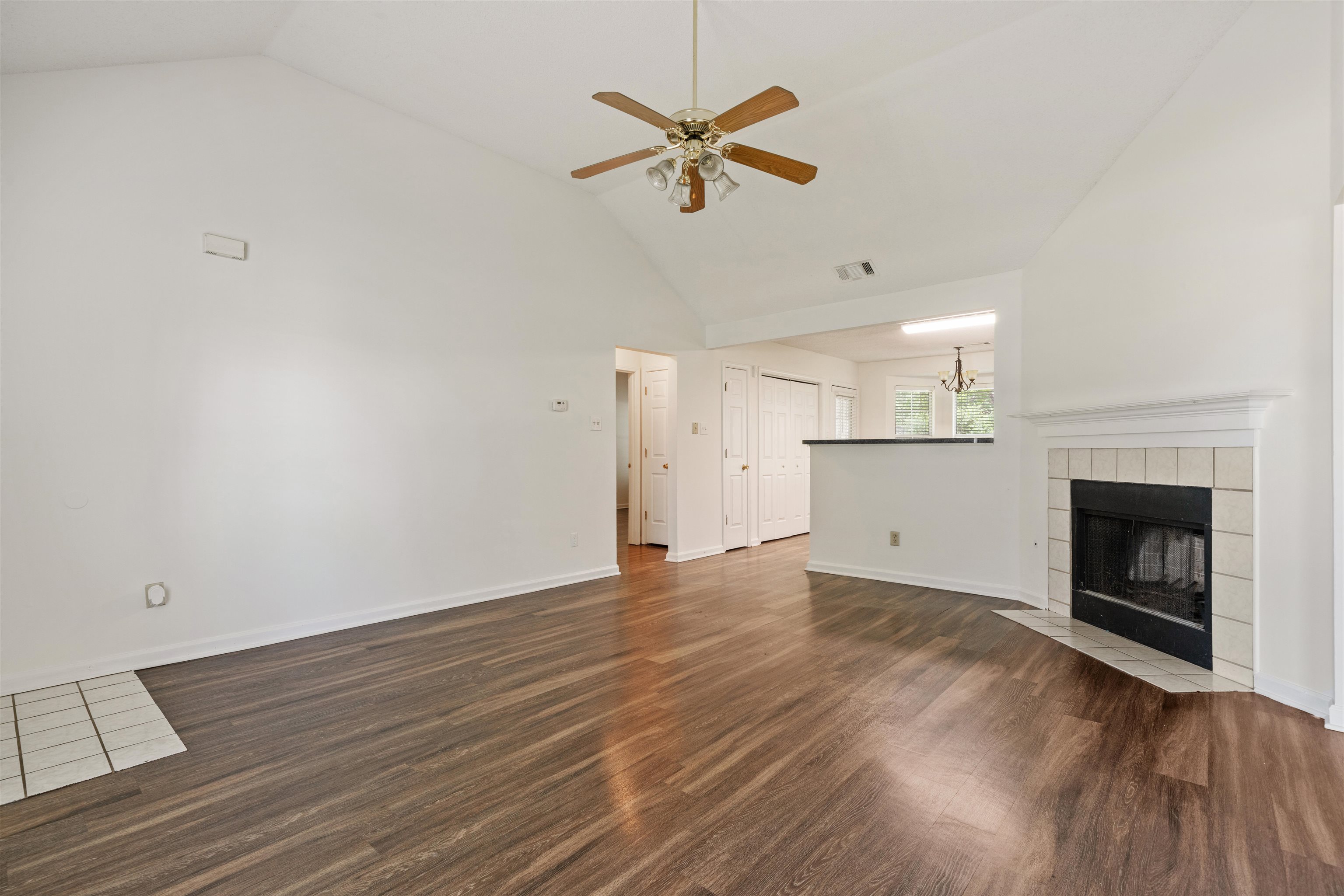 Living room featuring high vaulted ceiling, a tiled fireplace, ceiling fan, and hardwood / wood-style floors