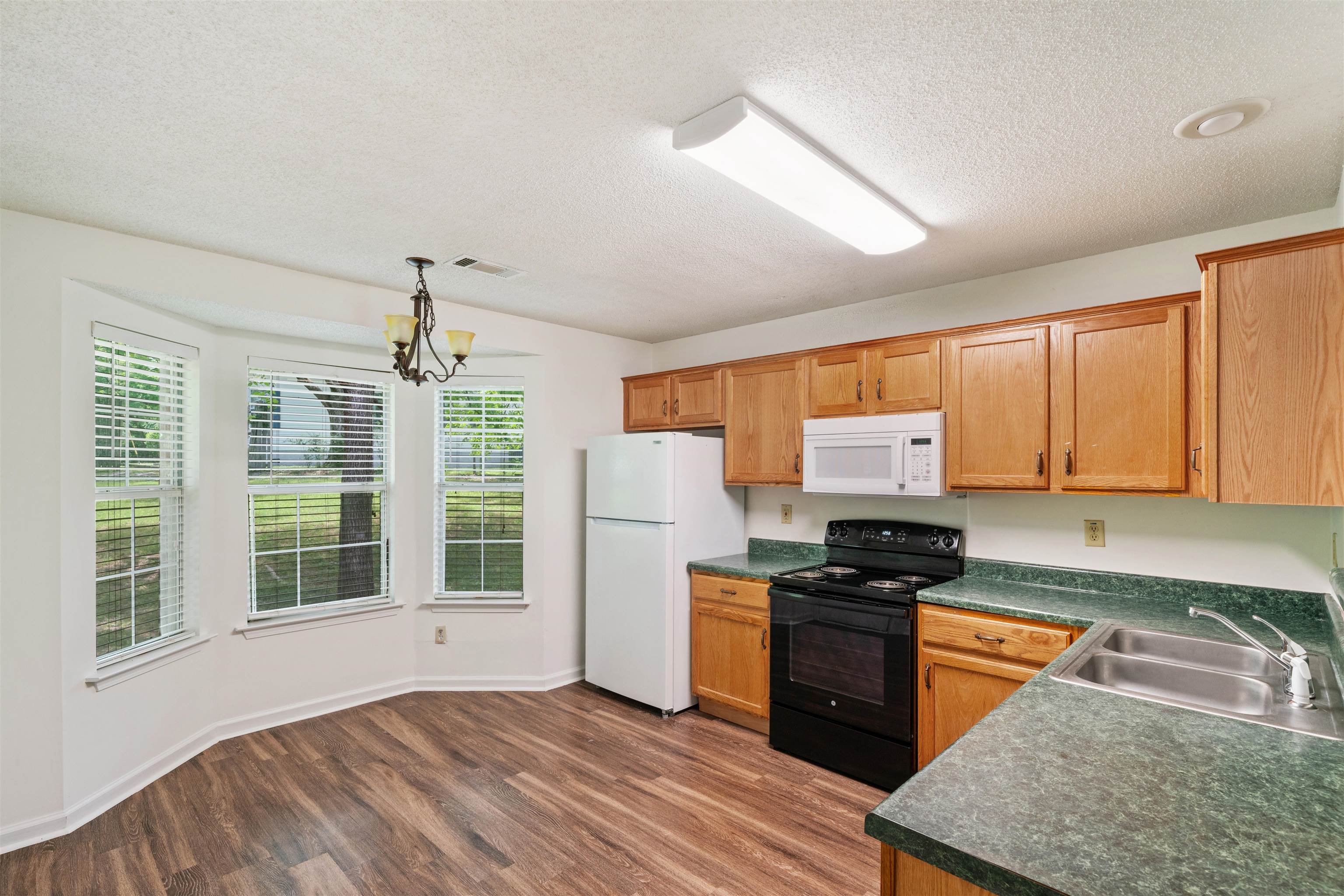 Kitchen with Breakfast Room light fixture, white appliances, stainless steel sink, and dark hardwood / wood-style floors, microwave, black range, and cabinets with crown molding