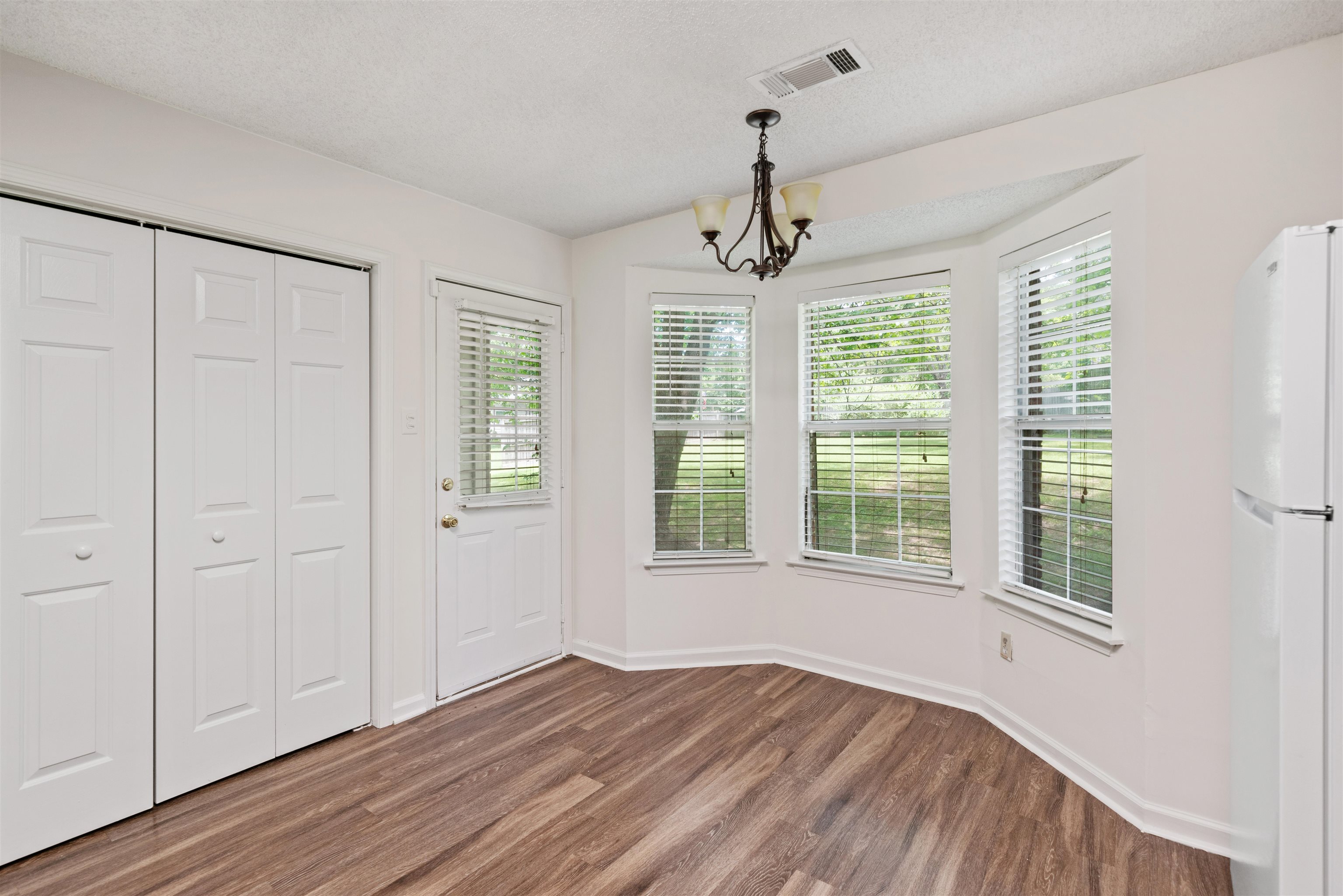 Dining Area with bump out space with multiple windows, white fridge, and hardwood / wood-style flooring