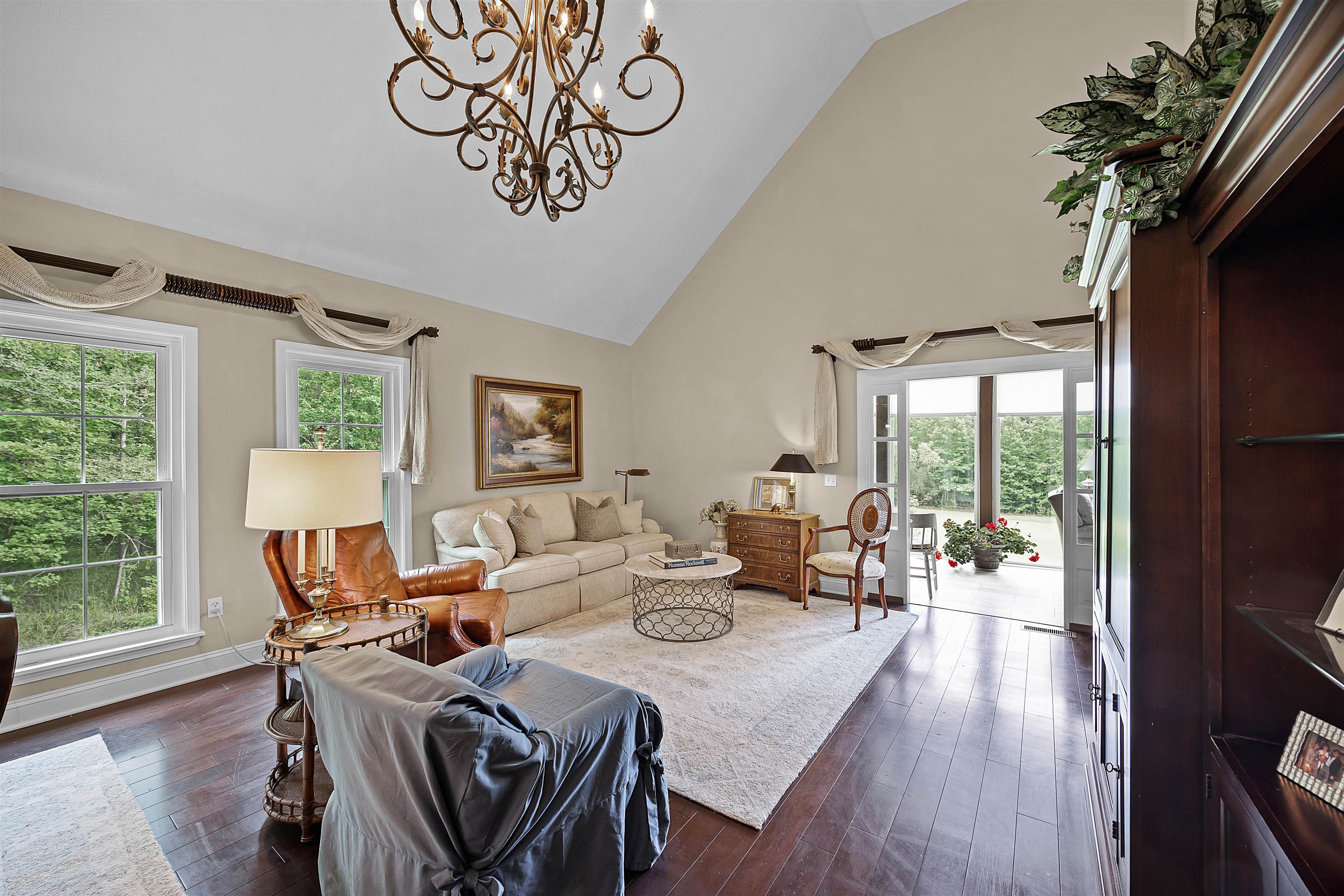 Living room with a notable chandelier, high vaulted ceiling, a healthy amount of sunlight, and wood-type flooring