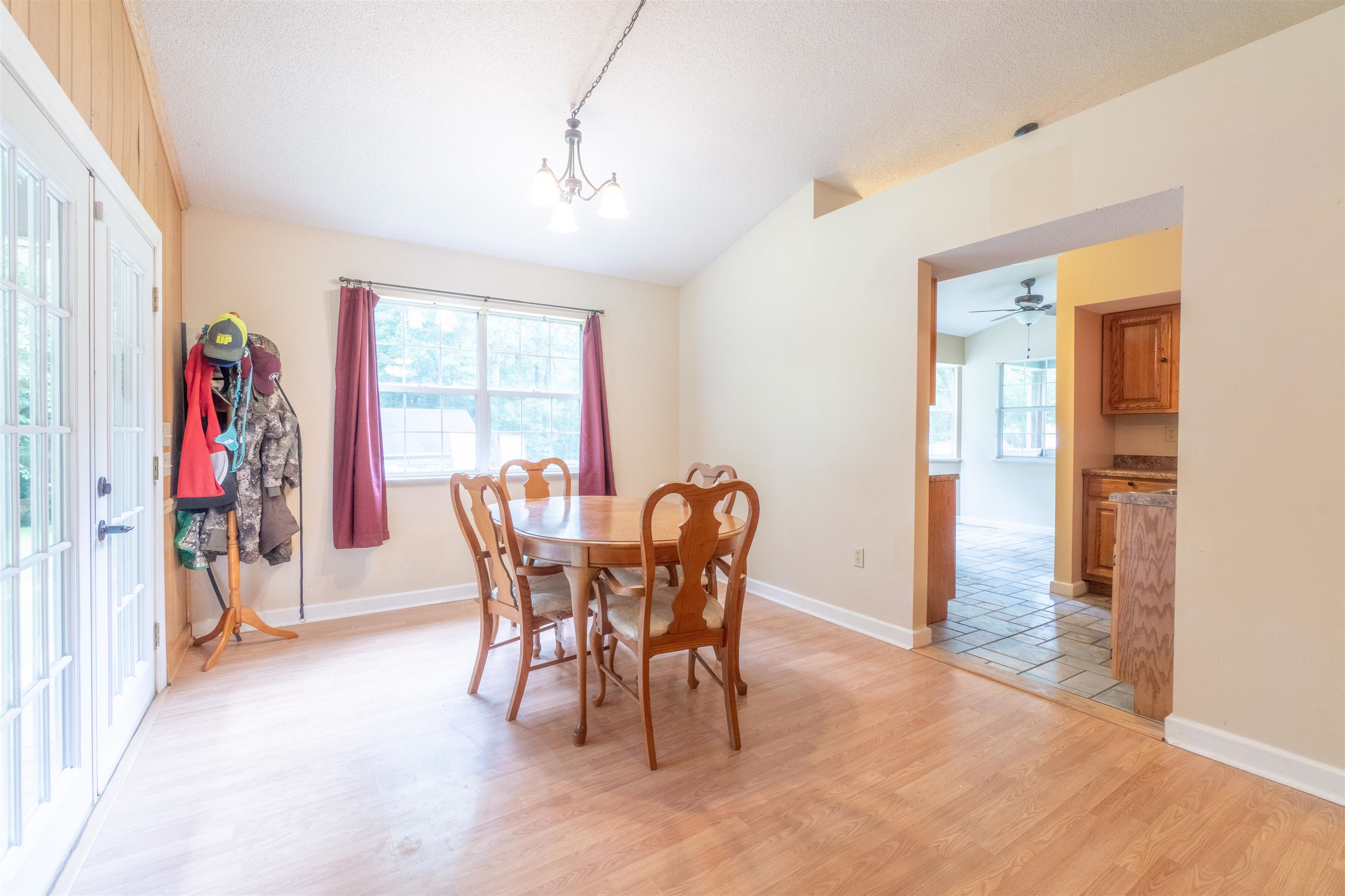 Dining area with vaulted ceiling, ceiling fan with notable chandelier, and light hardwood / wood-style floors