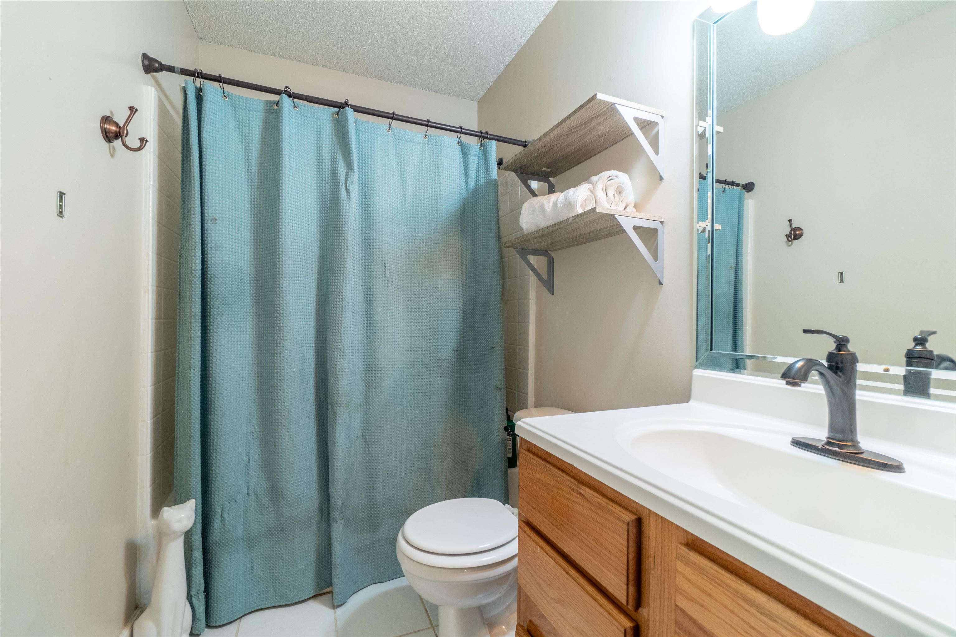 Bathroom with tile patterned floors, vanity, a textured ceiling, and toilet