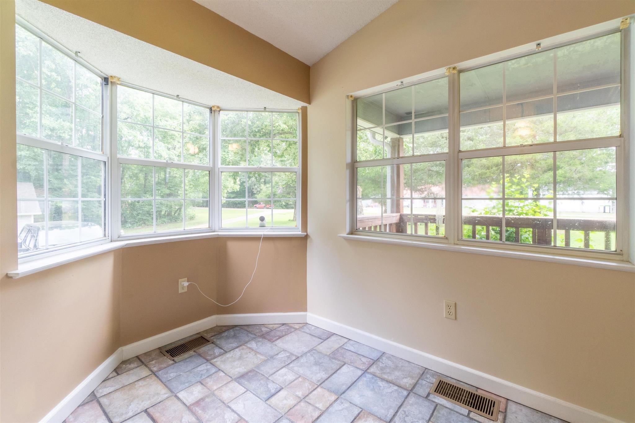 Tiled empty room with lofted ceiling and plenty of natural light