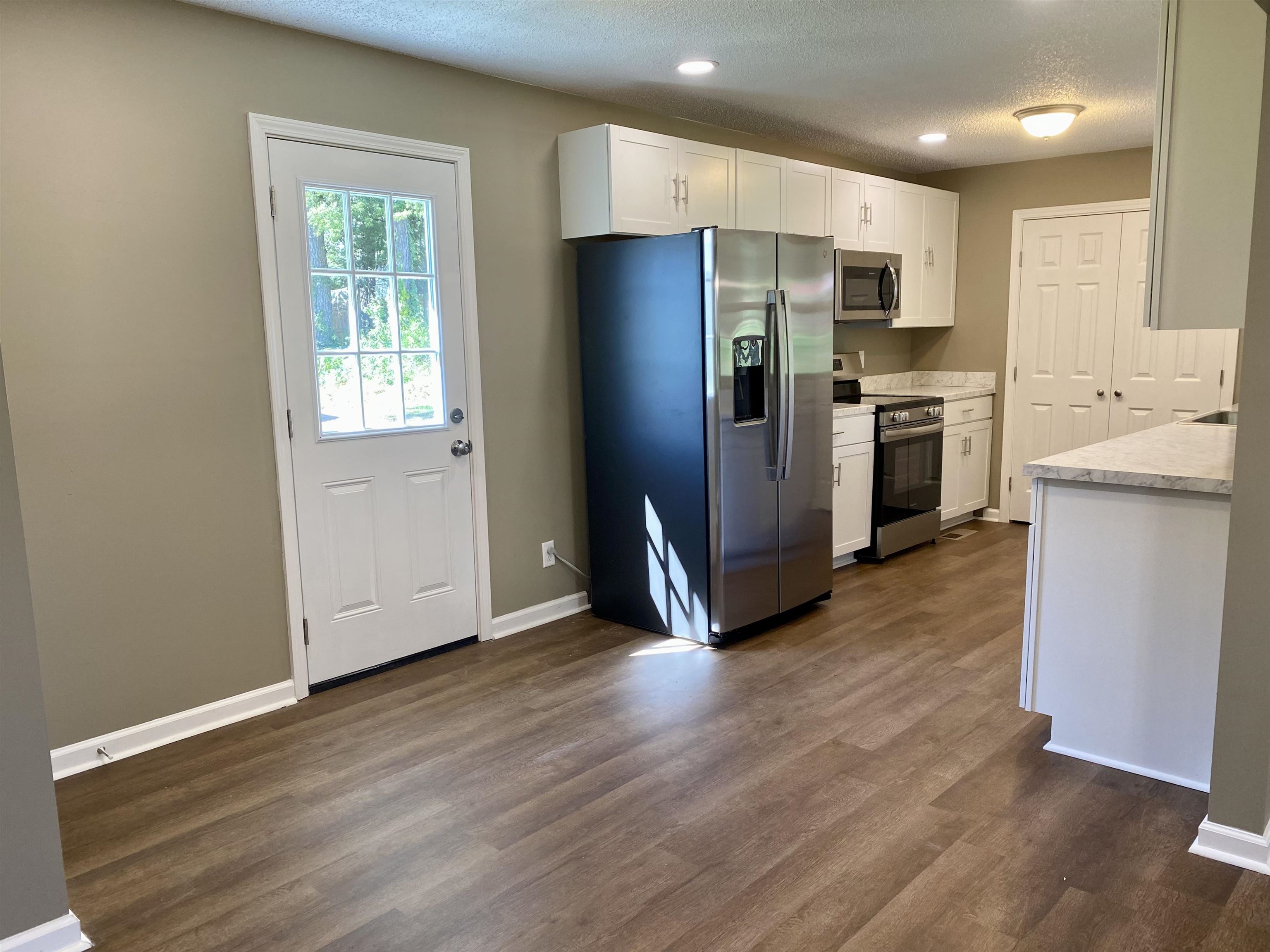 Kitchen featuring white cabinetry, dark hardwood / wood-style floors, and appliances with stainless steel finishes