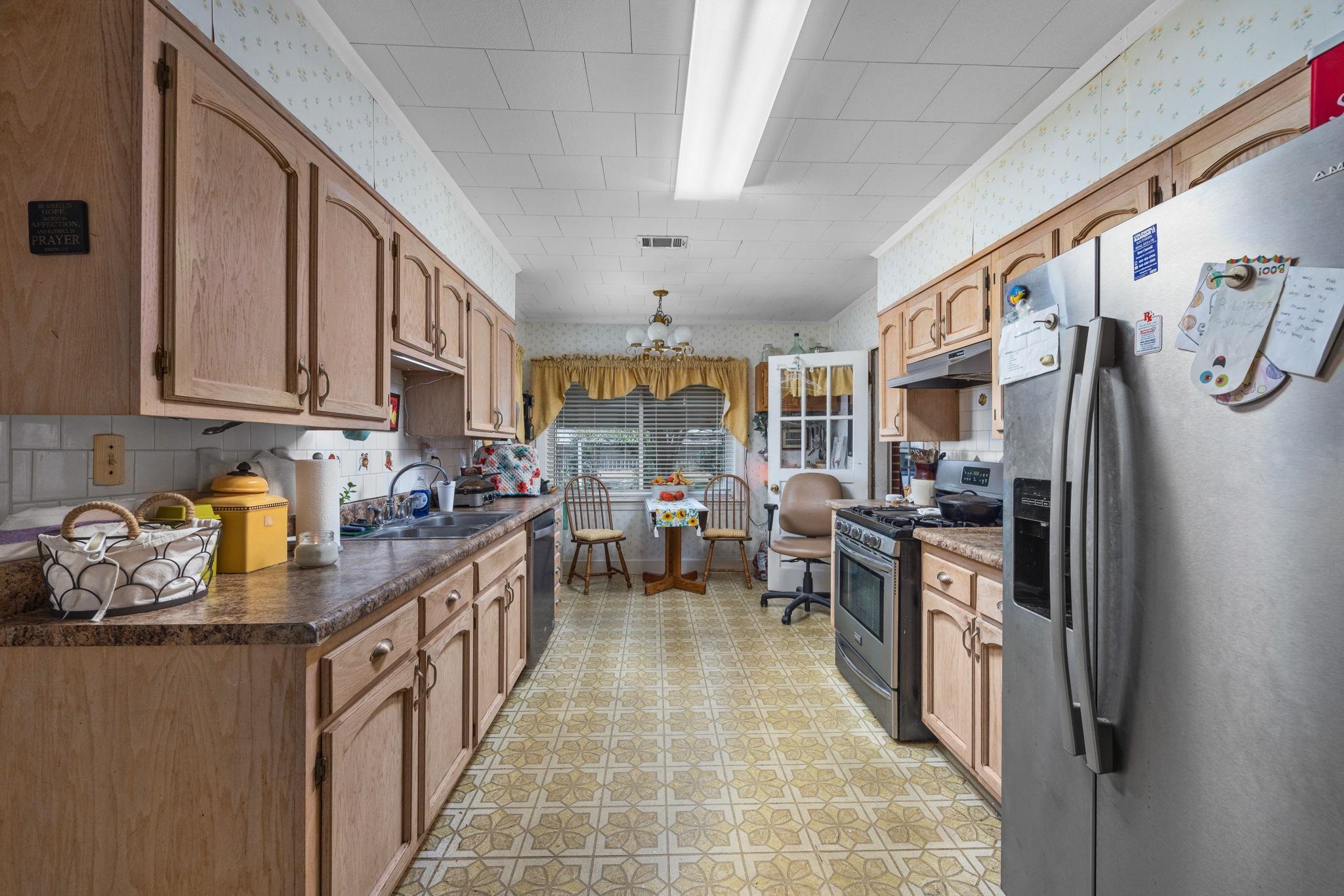 Kitchen with a notable chandelier, sink, light tile patterned floors, and stainless steel appliances