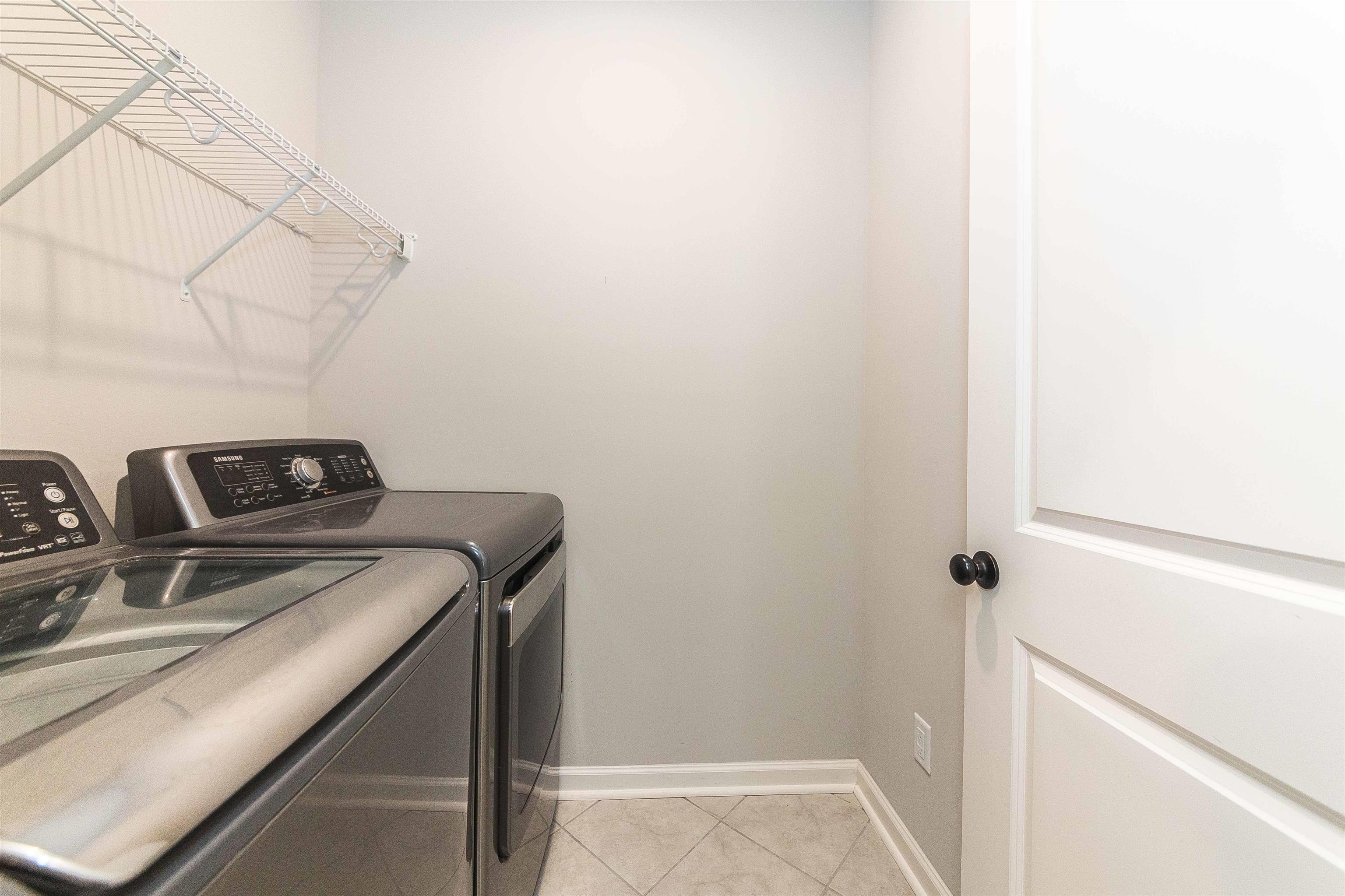 Clothes washing area with light tile patterned flooring and washing machine and dryer