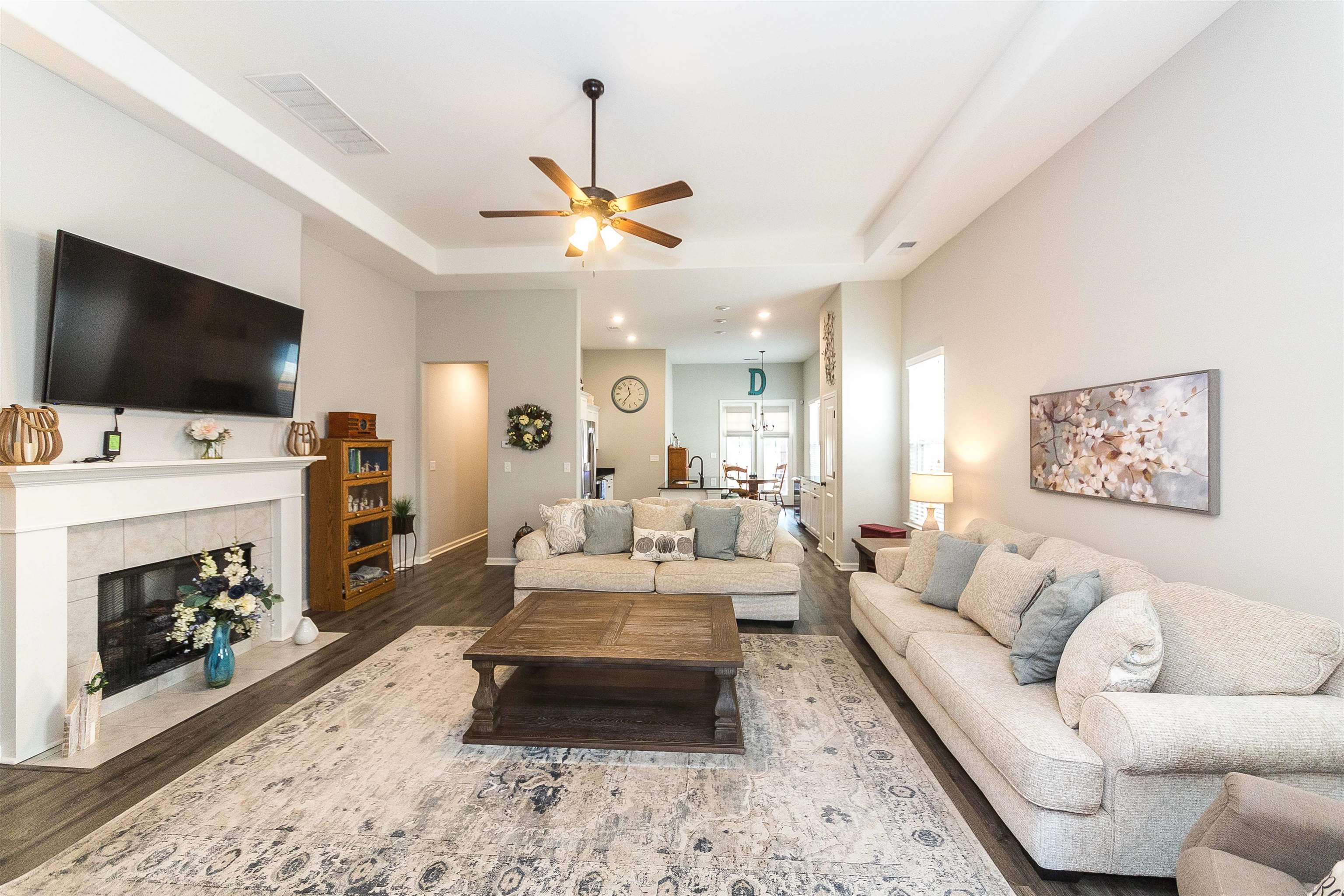 Living room with a tile fireplace, a tray ceiling, dark hardwood / wood-style flooring, and ceiling fan