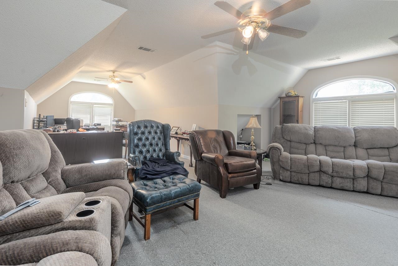 Living room with ceiling fan, vaulted ceiling, and plenty of natural light