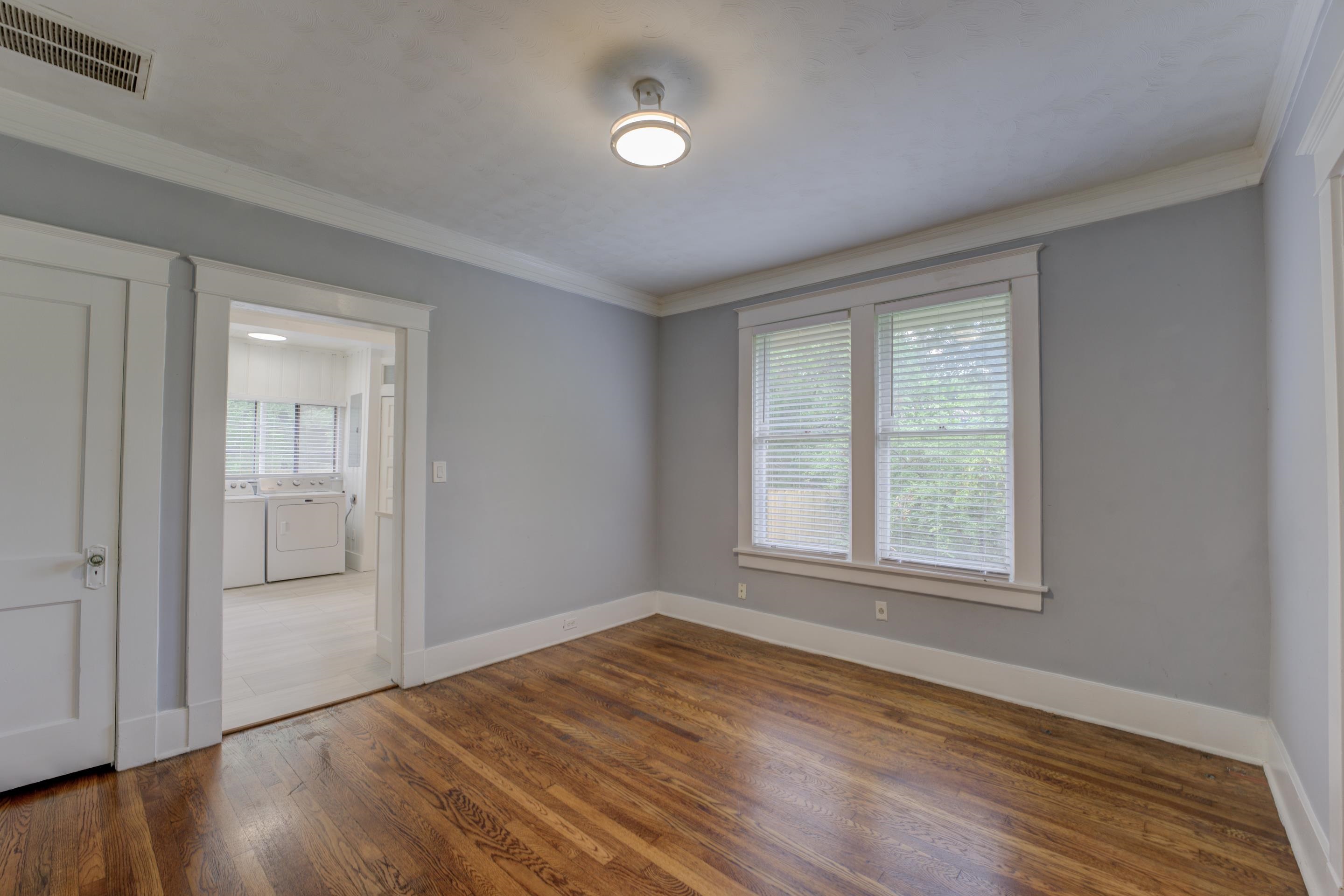 Spare room with hardwood / wood-style flooring, washing machine and dryer, and ornamental molding