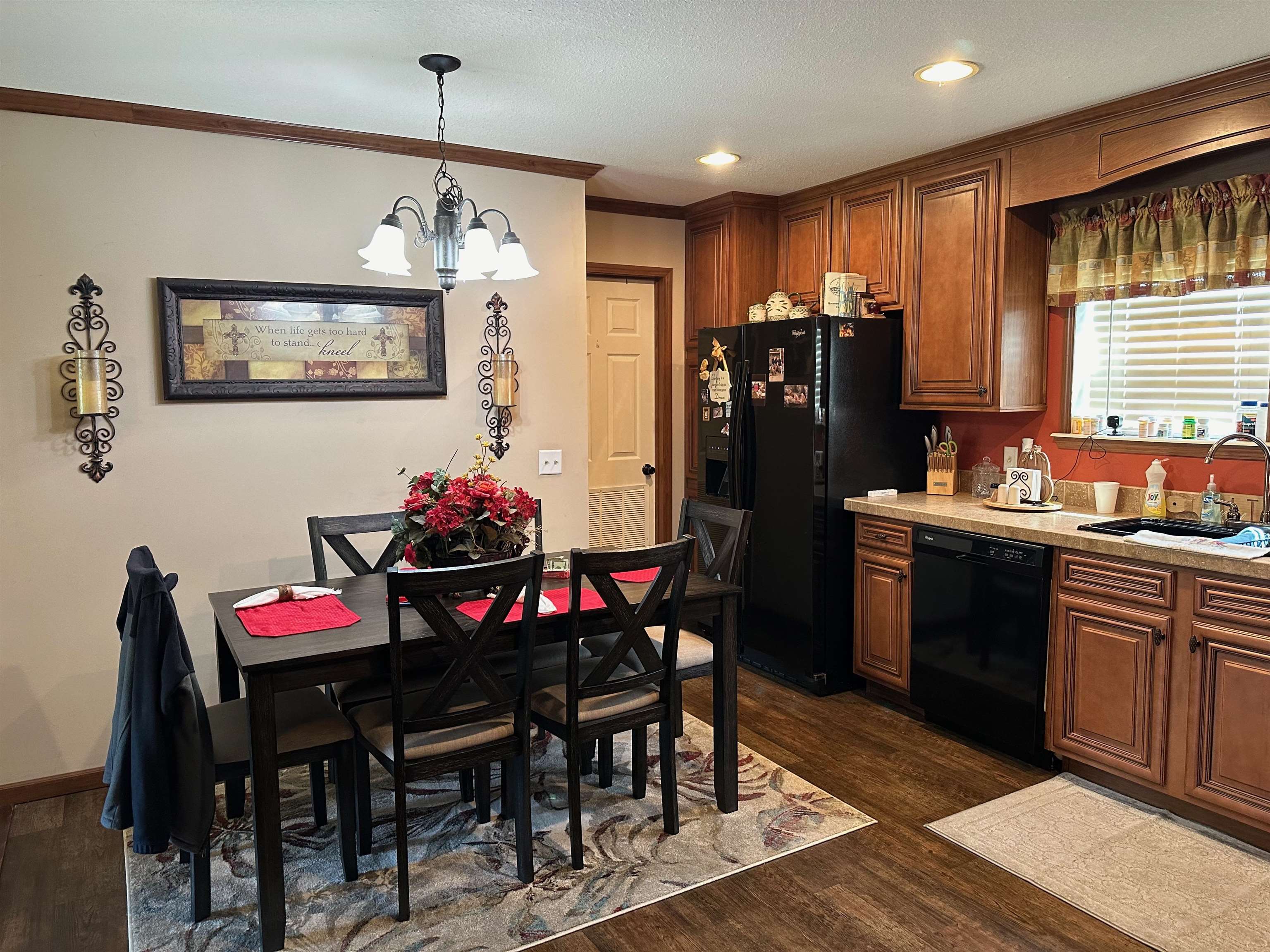 Kitchen with black appliances, sink, decorative light fixtures, crown molding, and dark wood-type flooring