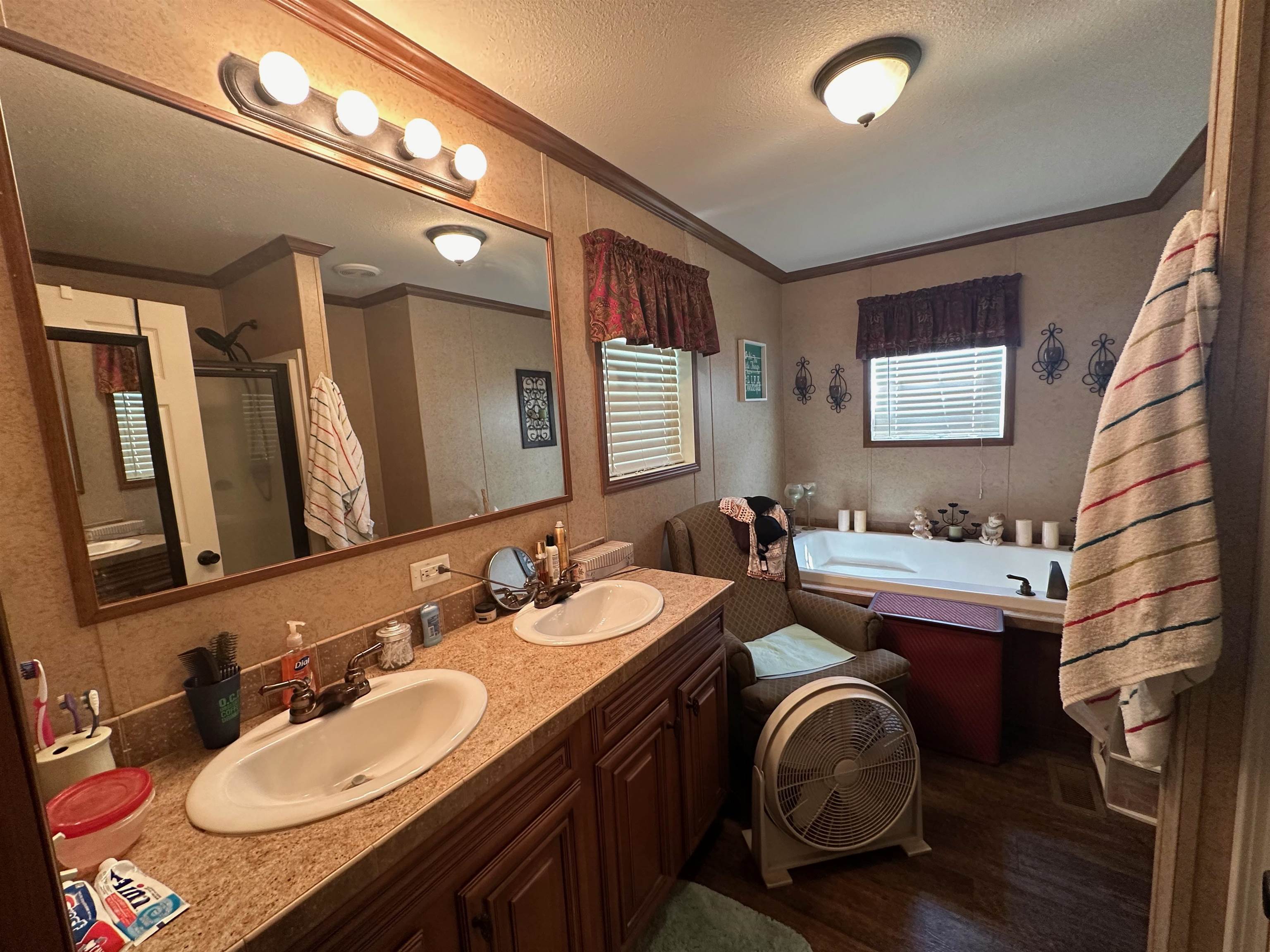 Bathroom with wood-type flooring, decorative backsplash, crown molding, dual vanity, and a tub to relax in