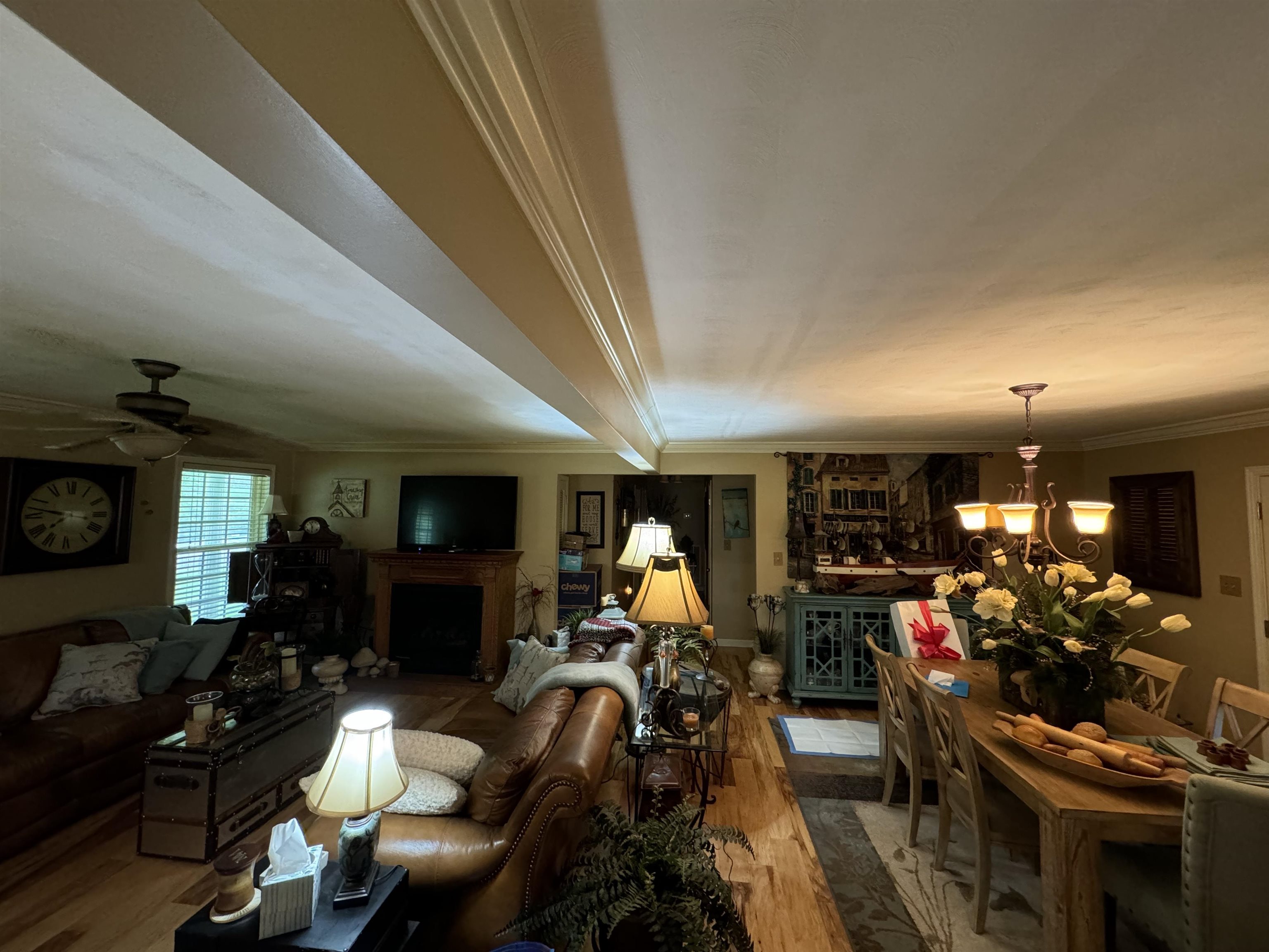 Living room with ceiling fan with notable chandelier, hardwood / wood-style floors, and ornamental molding