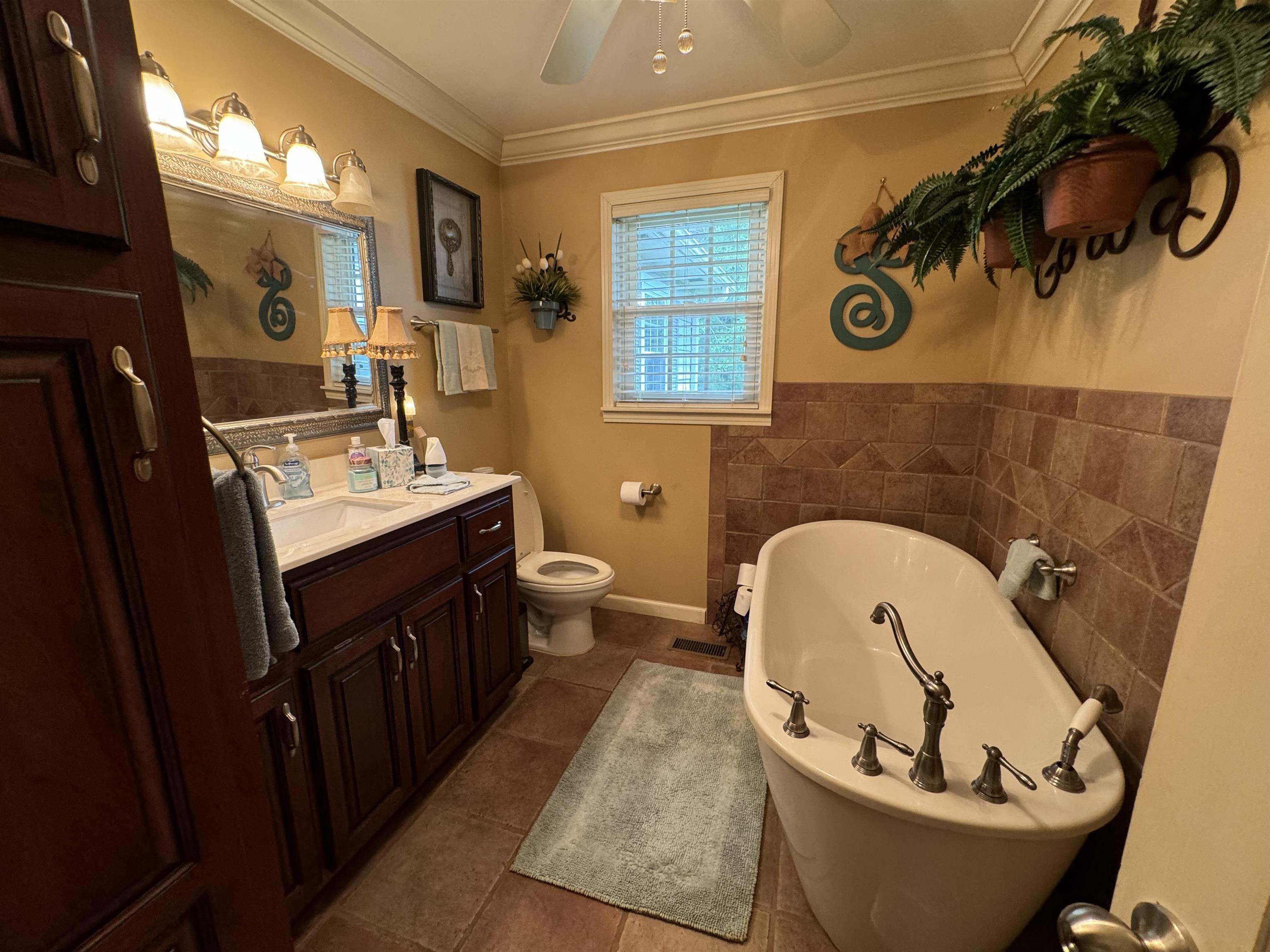 Bathroom with tile patterned flooring, a washtub, toilet, vanity, and ceiling fan