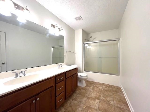 Bathroom featuring dual vanity, a textured ceiling, toilet, and tile patterned flooring