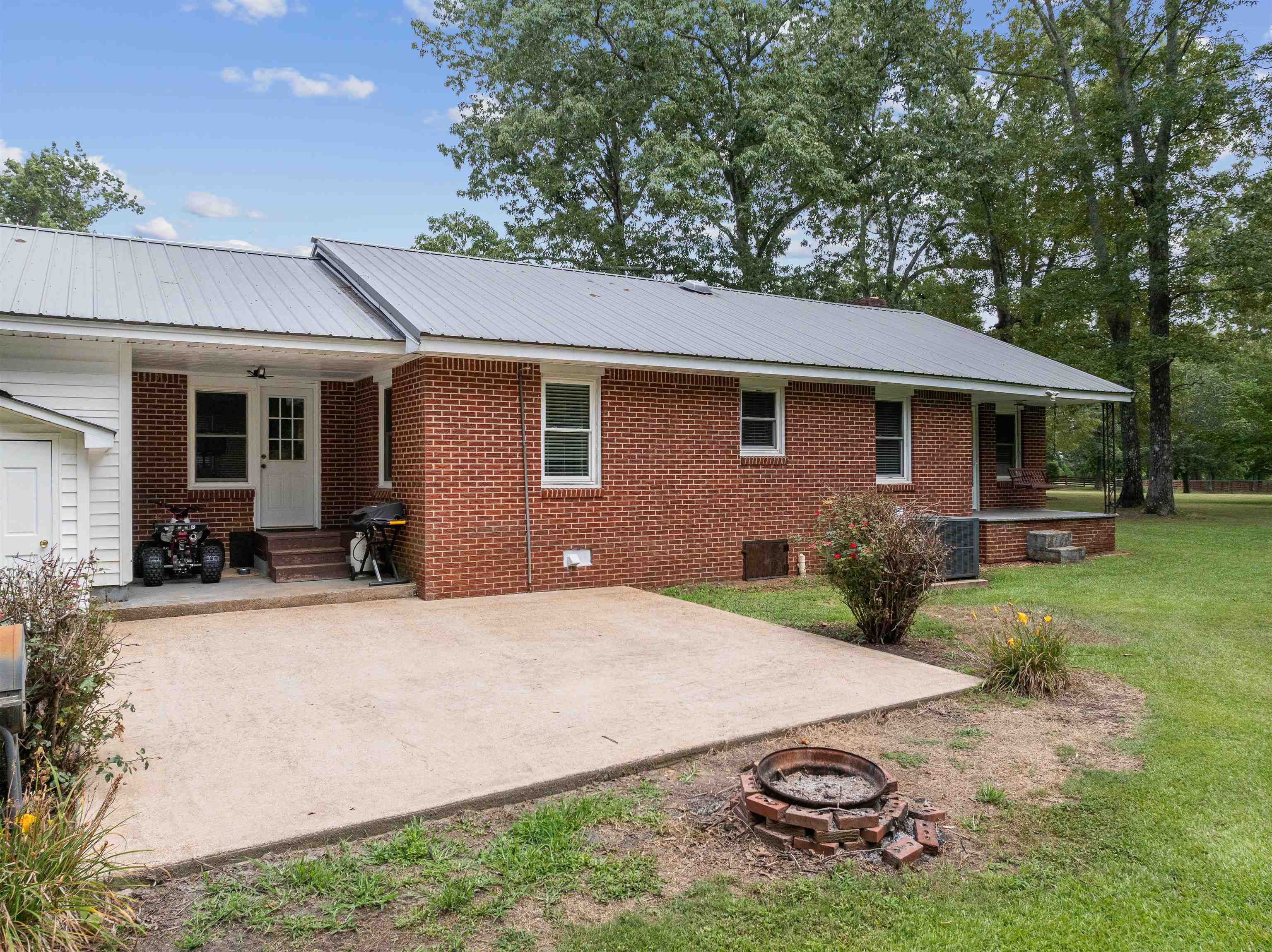 Back of property with a fire pit, a patio, a yard, and central AC