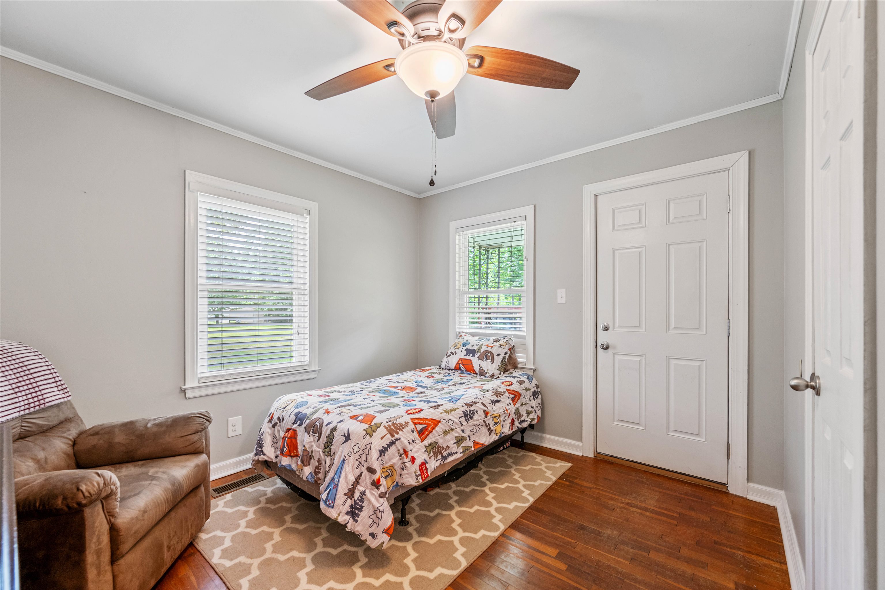 Bedroom with multiple windows, ceiling fan, crown molding, and dark wood-type flooring