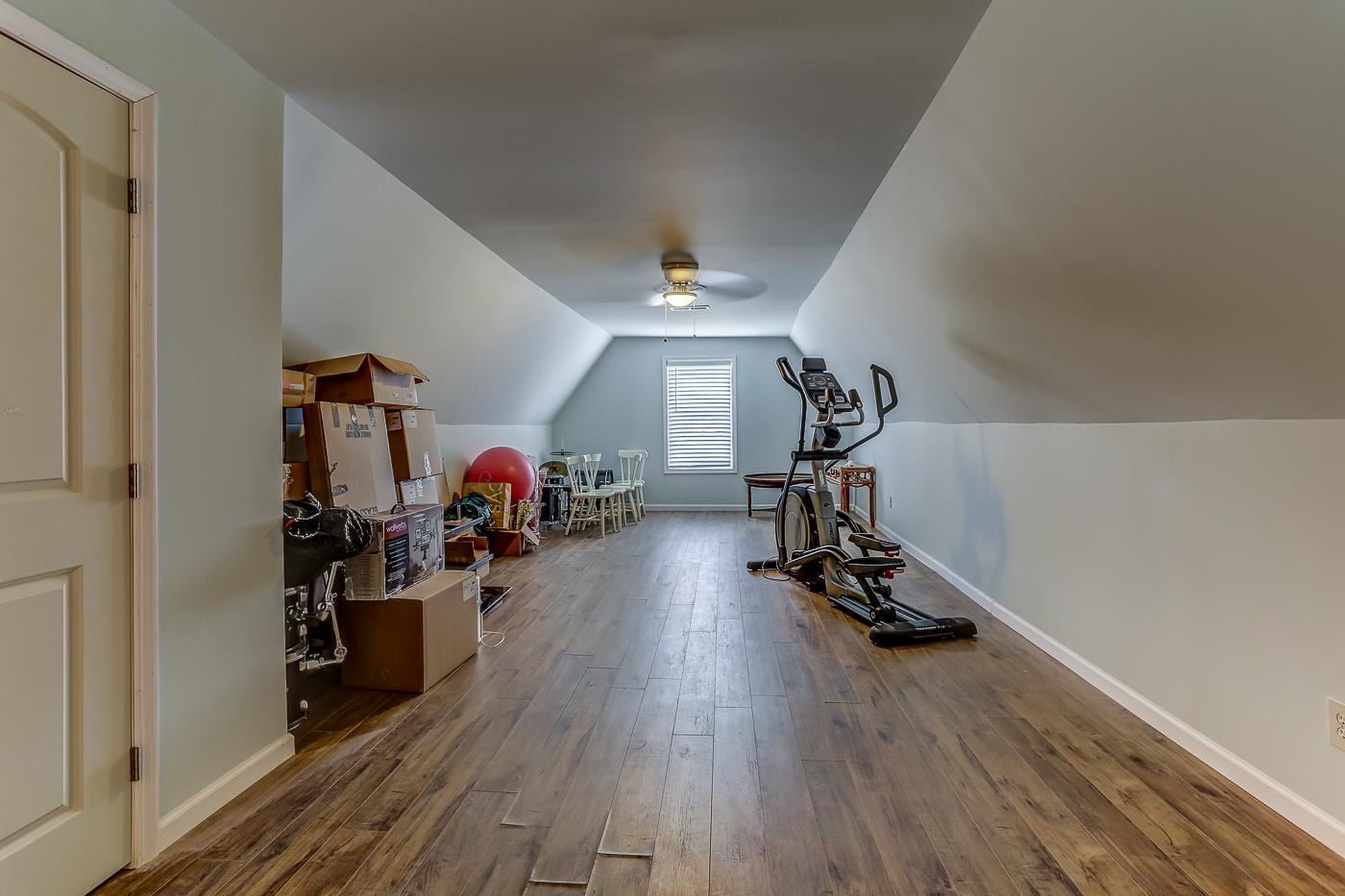 Workout area with ceiling fan, lofted ceiling, and hardwood / wood-style floors