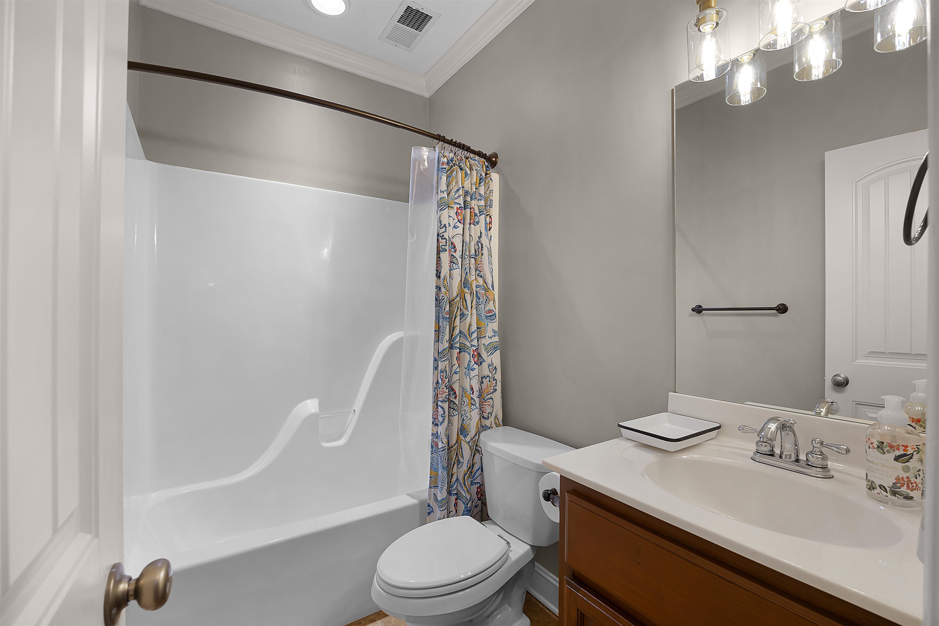 Full bathroom with vanity, crown molding, toilet, and shower / bathtub combination with curtain