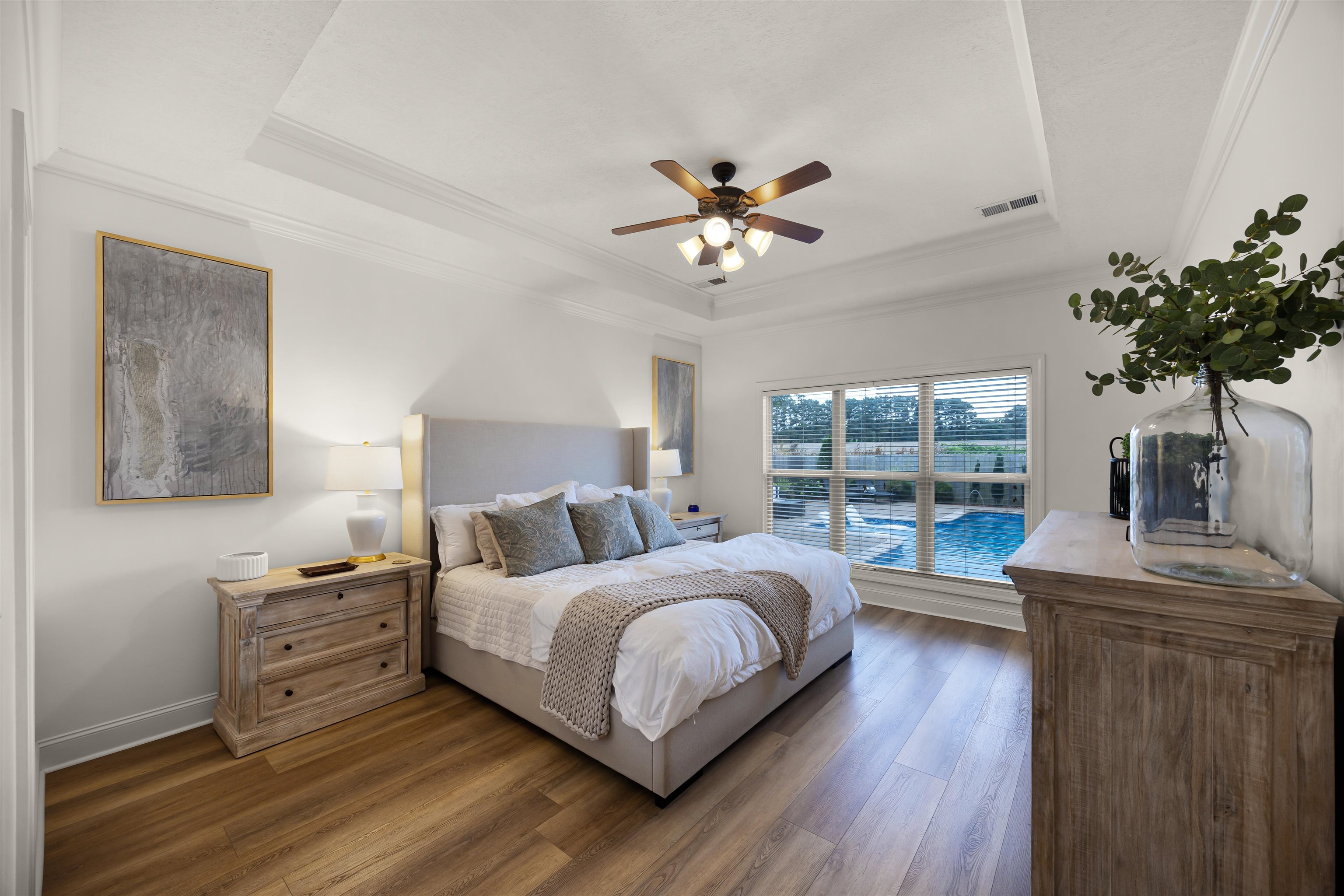 Bedroom featuring a raised ceiling, dark hardwood / wood-style flooring, ornamental molding, and ceiling fan