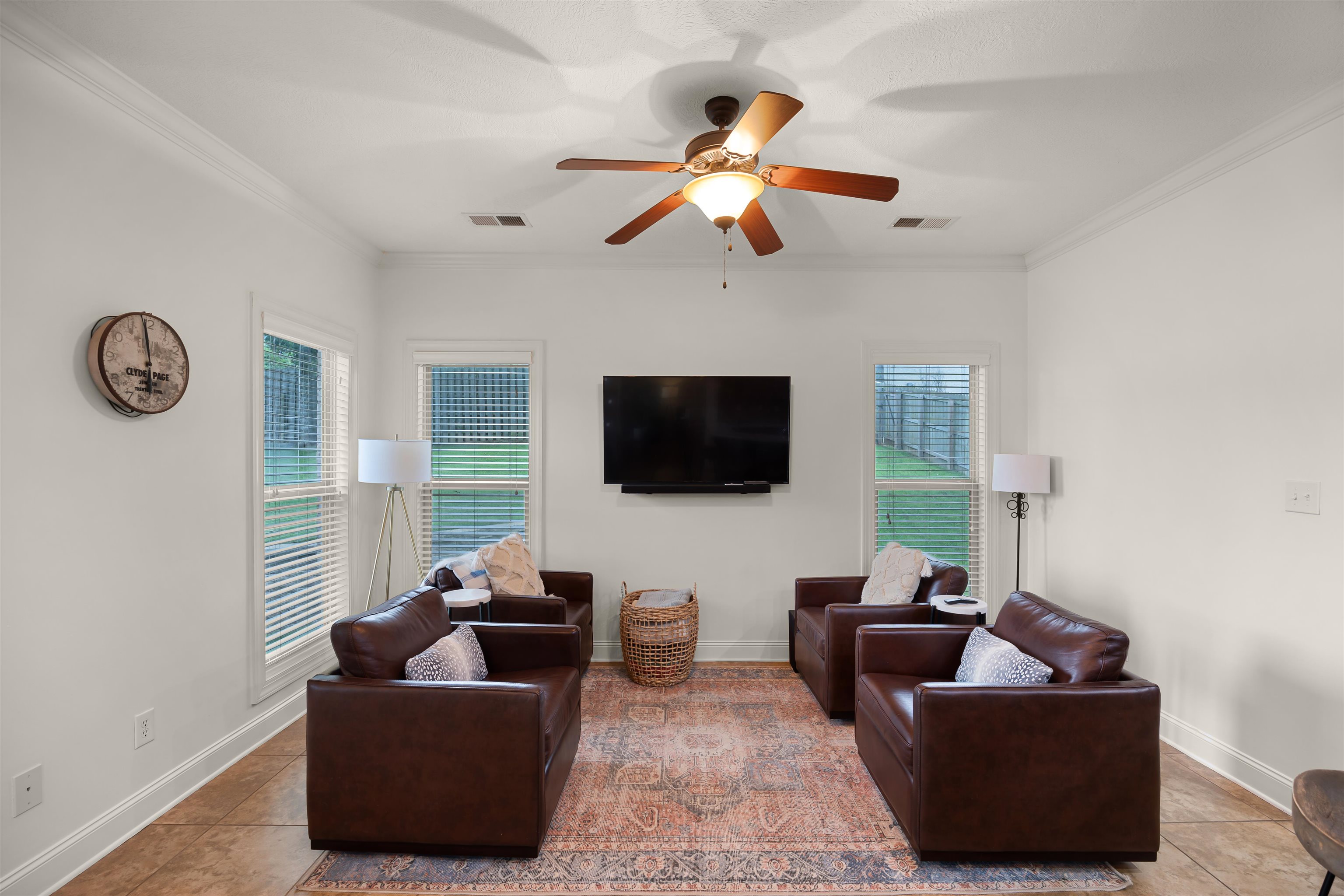 Tiled living room with ornamental molding, ceiling fan, and plenty of natural light