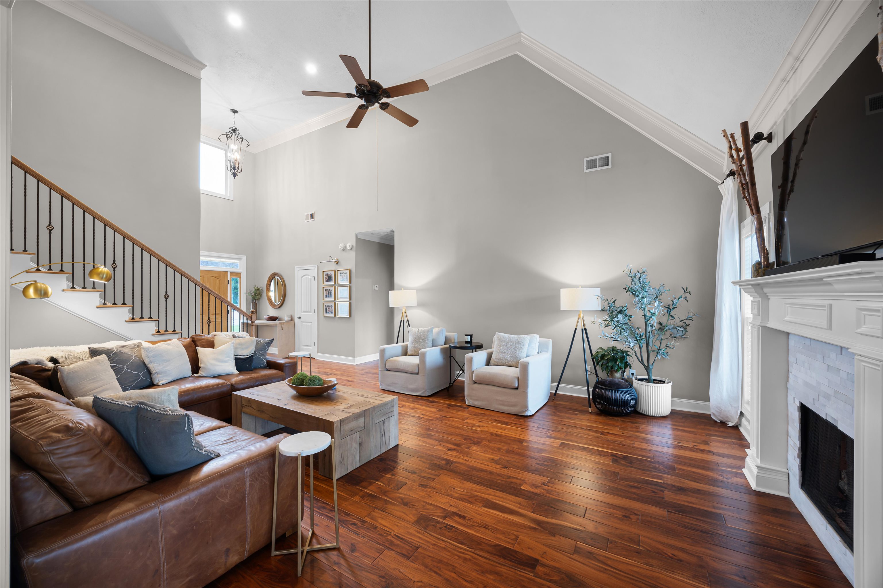 Living room featuring a tile fireplace, high vaulted ceiling, and ornamental molding
