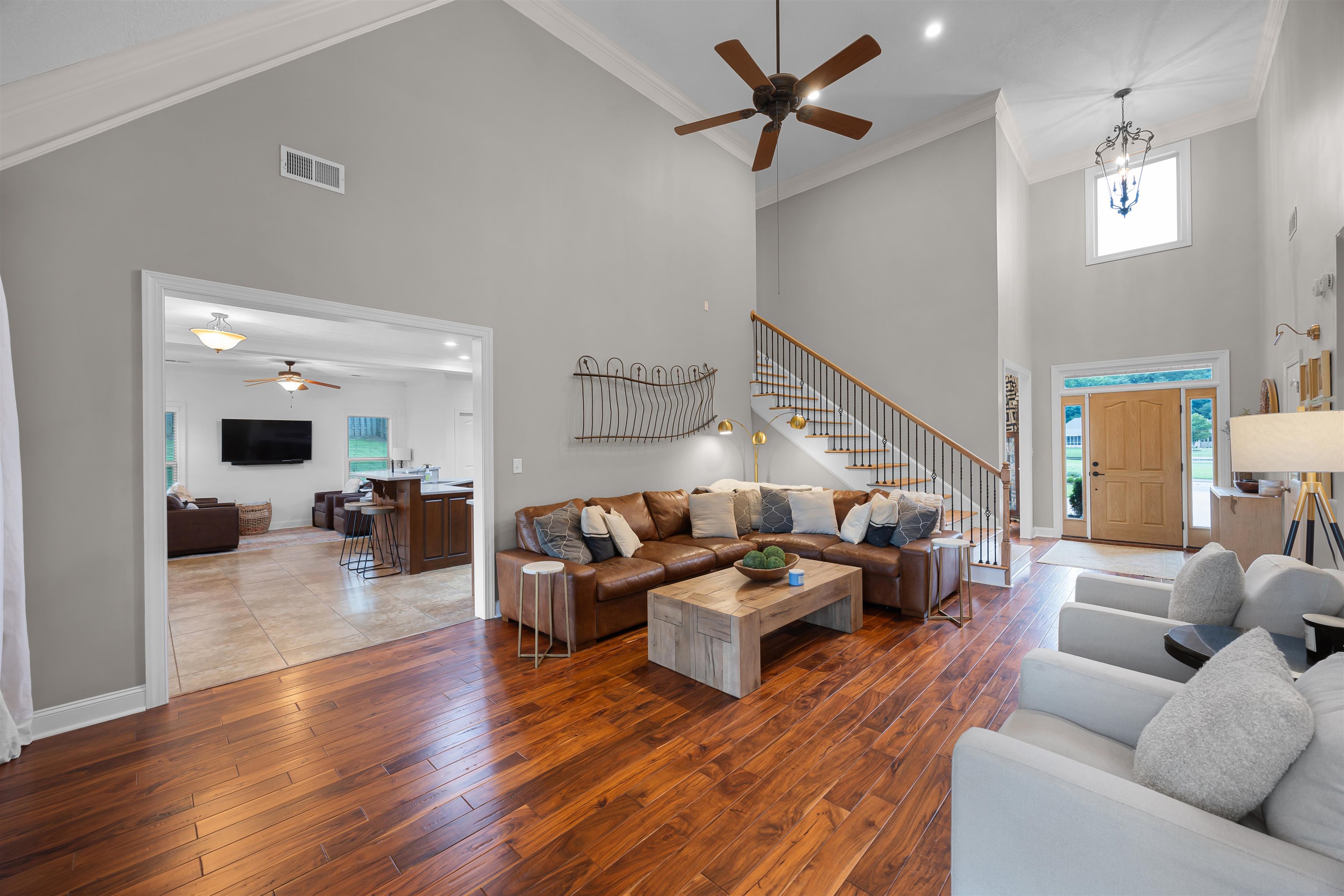 Living room featuring wood-type flooring, ceiling fan with notable chandelier, and high vaulted ceiling