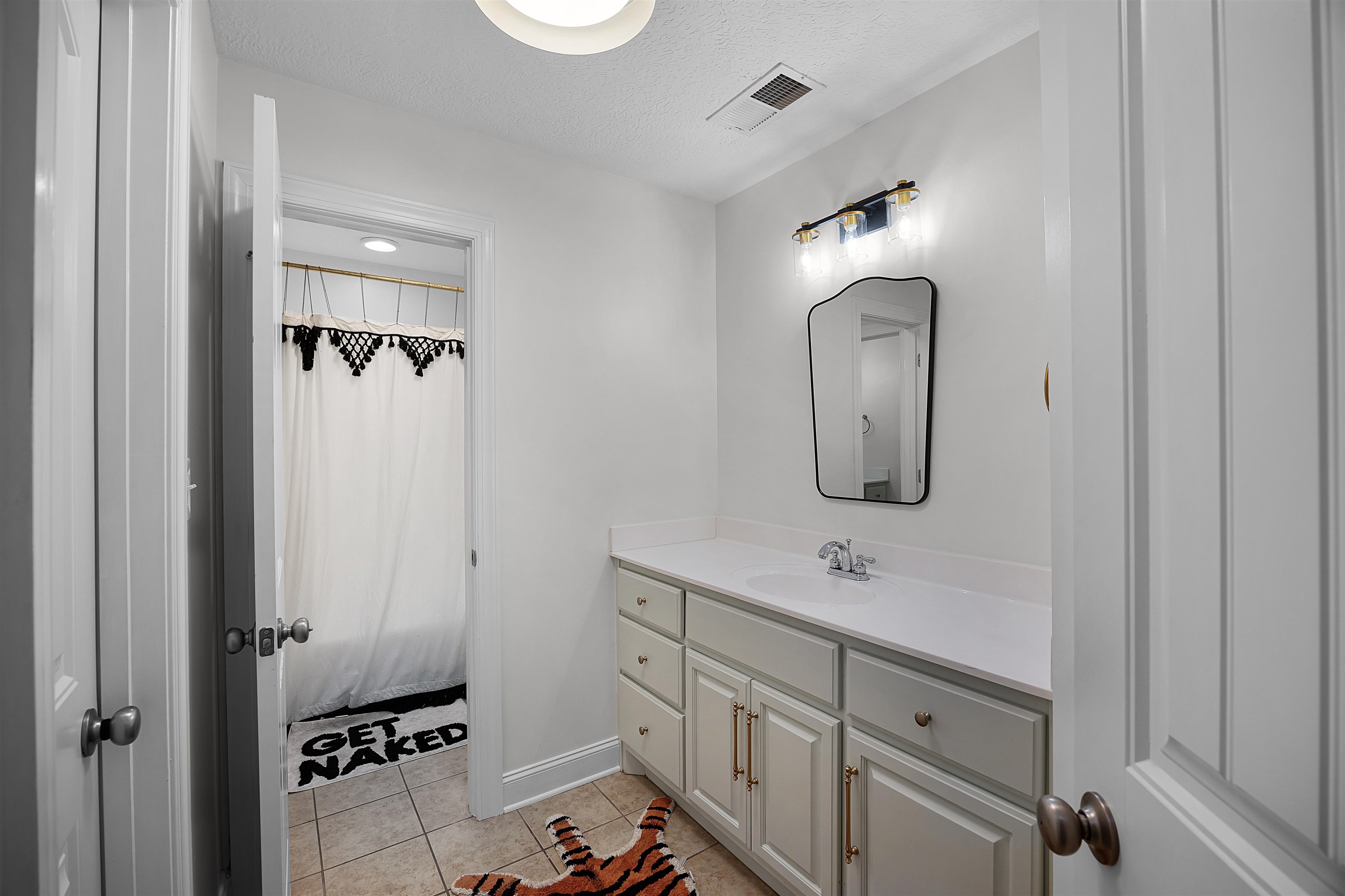 Bathroom with tile patterned floors, vanity, and a textured ceiling