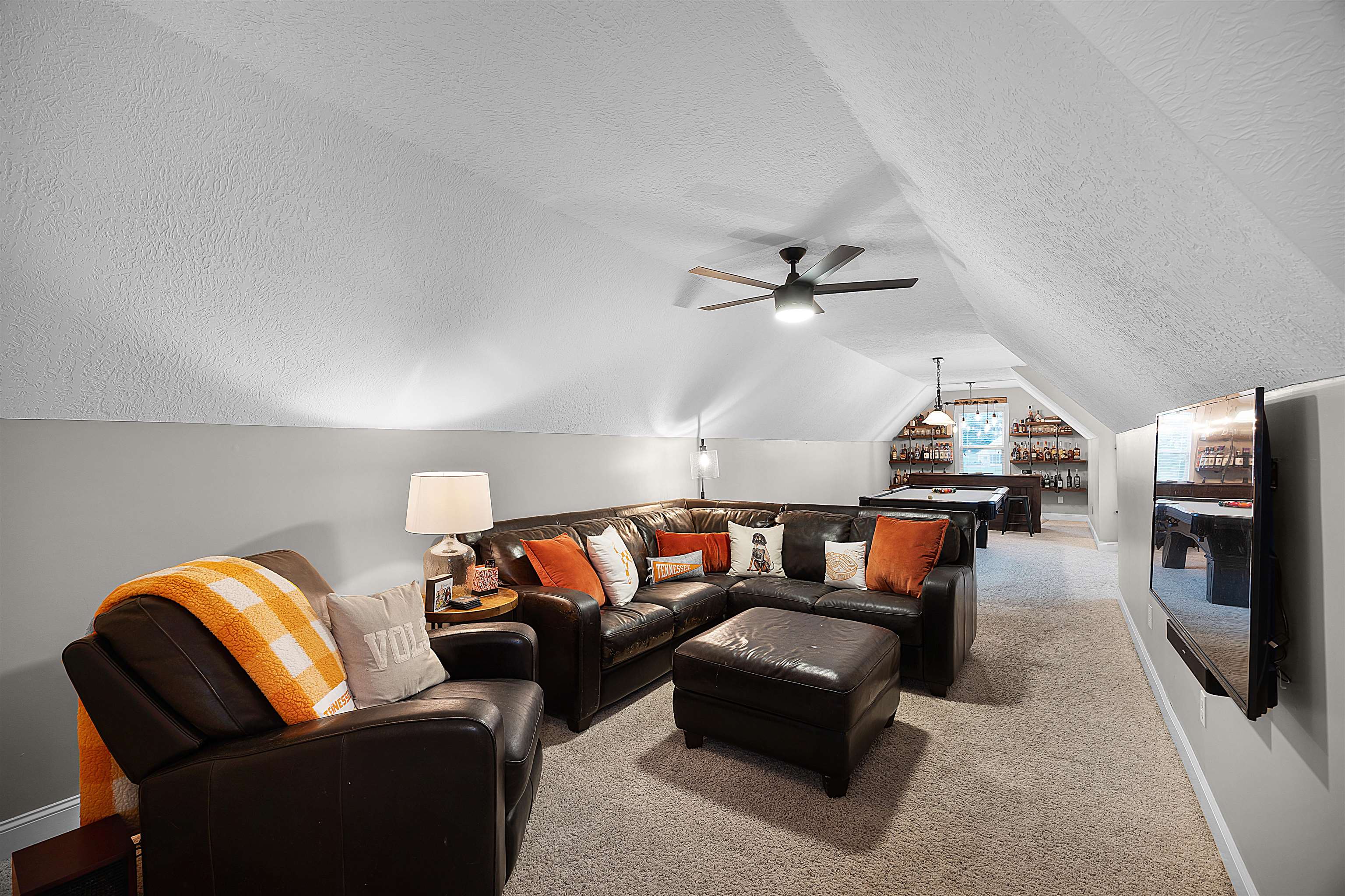 Carpeted living room with a textured ceiling, ceiling fan, and vaulted ceiling
