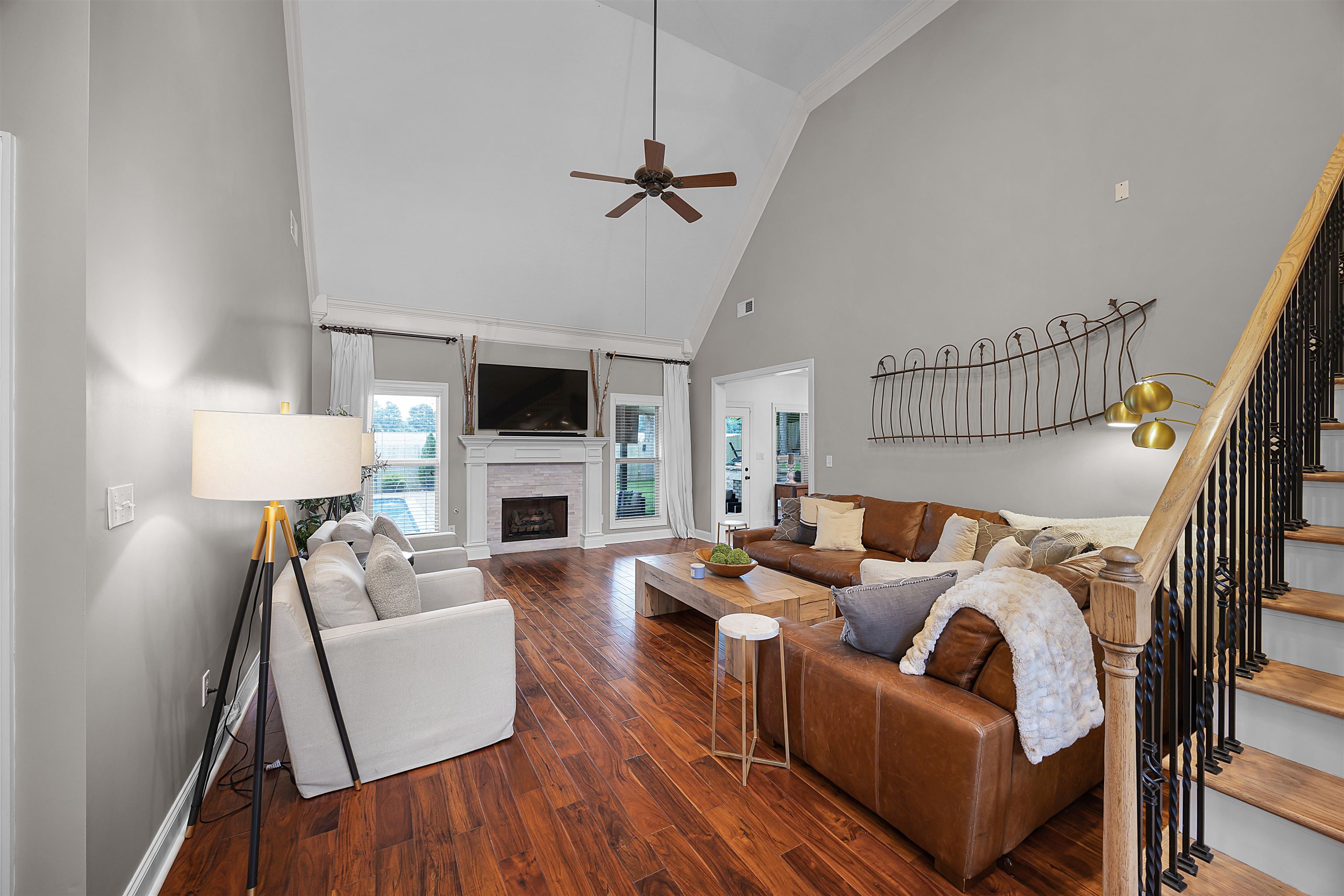 Living room with high vaulted ceiling, dark wood-type flooring, and ceiling fan