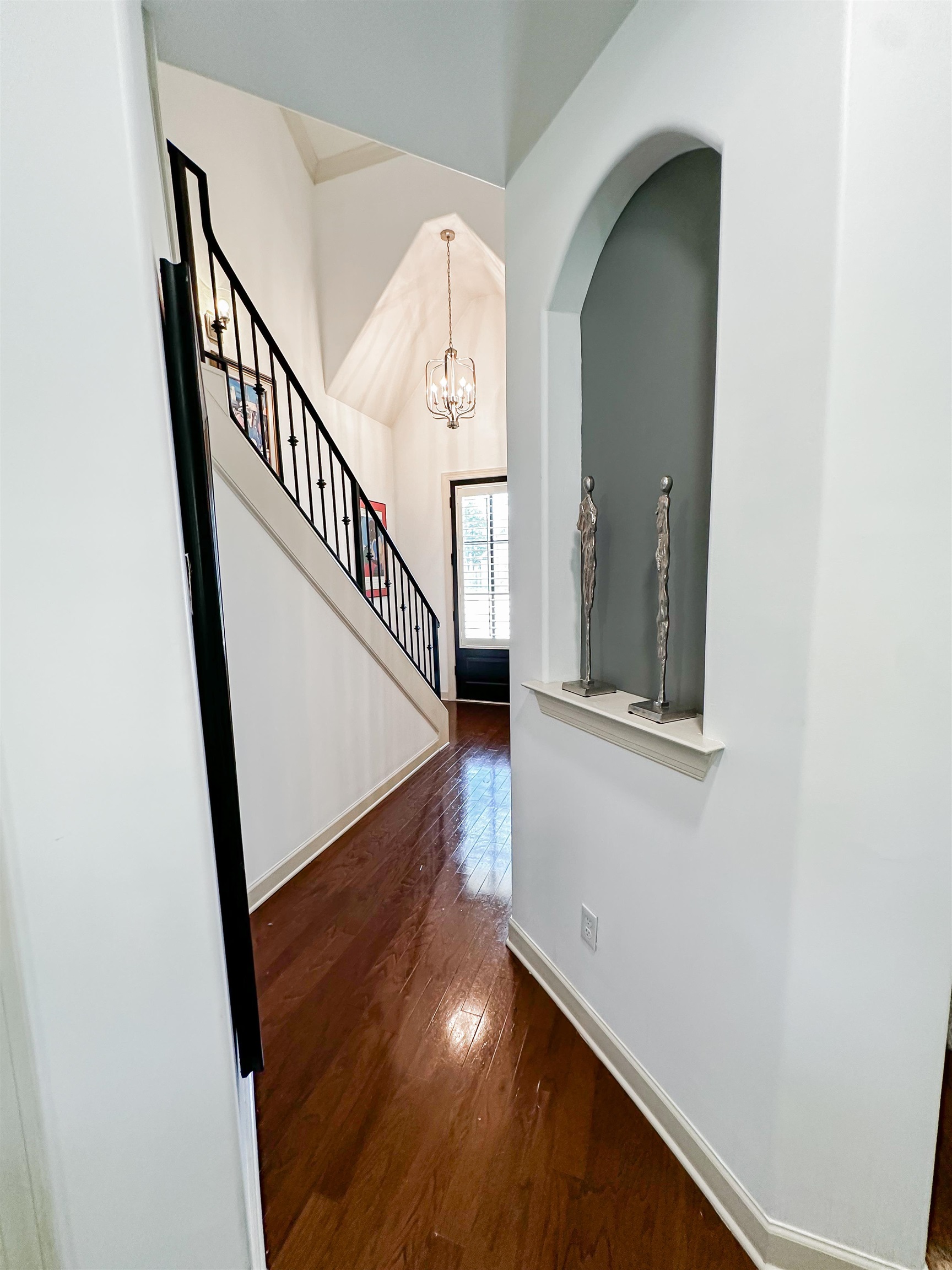 Foyer with dark hardwood / wood-style floors, lofted ceiling, and an inviting chandelier